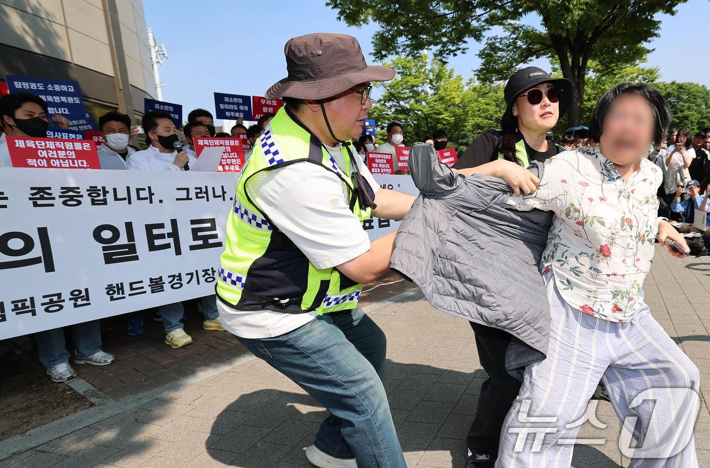본문 이미지 - 11일 서울 송파구 올림픽공원 핸드볼경기장 앞에서 열린 핸드볼경기장 입주 체육단체 직원들의 업무 정상화 호소문 발표 기자회견 도중 한 여성이 기자회견을 가로막으며 항의하고 있다. 2026.6.11 ⓒ 뉴스1 오대일 기자