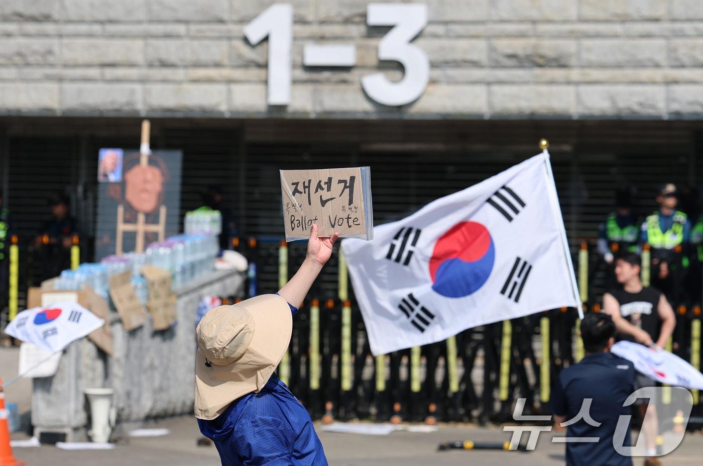 본문 이미지 - 제9회 전국동시지방선거 투표용지 부족 사태를 규탄하는 개표소 봉쇄 시위가 계속된 11일 서울 송파구 올림픽공원 핸드볼경기장 앞에서 시위대가 재선거를 요구하는 피켓을 들고 있다. 2026.6.11 ⓒ 뉴스1 오대일 기자