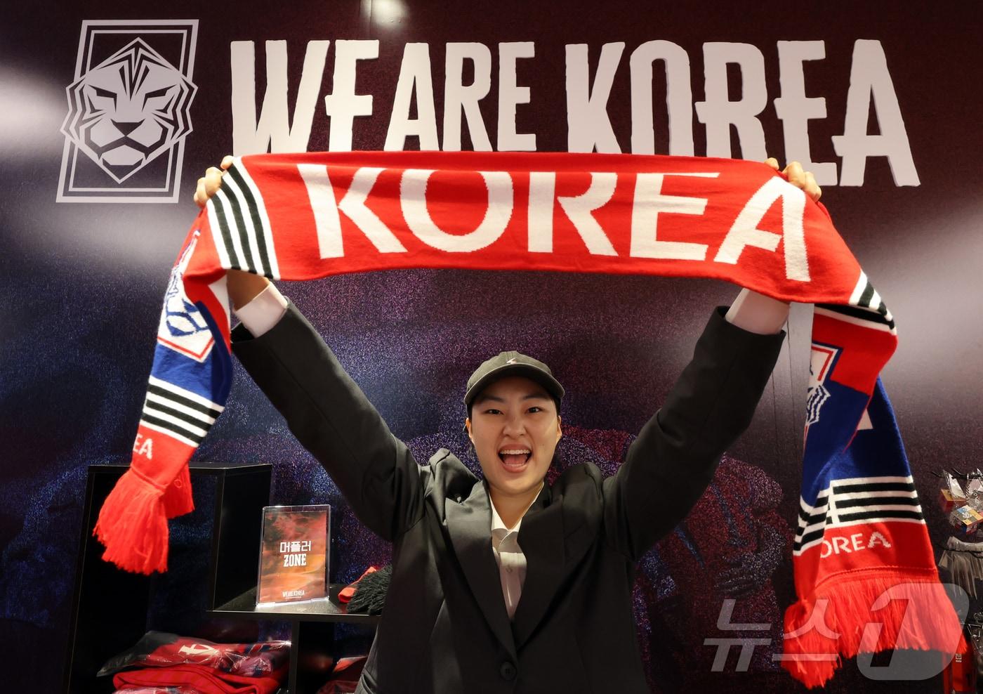본문 이미지 - 2026 북중미월드컵 체코와의 경기를 앞둔 11일 서울 영등포구 더현대 서울 팝업 공간에 마련된 대한축구협회(KFA)의 '대한민국 축구국가대표팀 : 팬들의 베이스캠프' 팝업스토어를 찾은 한 시민이 머플러를 들며 포즈를 취하고 있다. 2026.6.11 ⓒ 뉴스1 김진환 기자