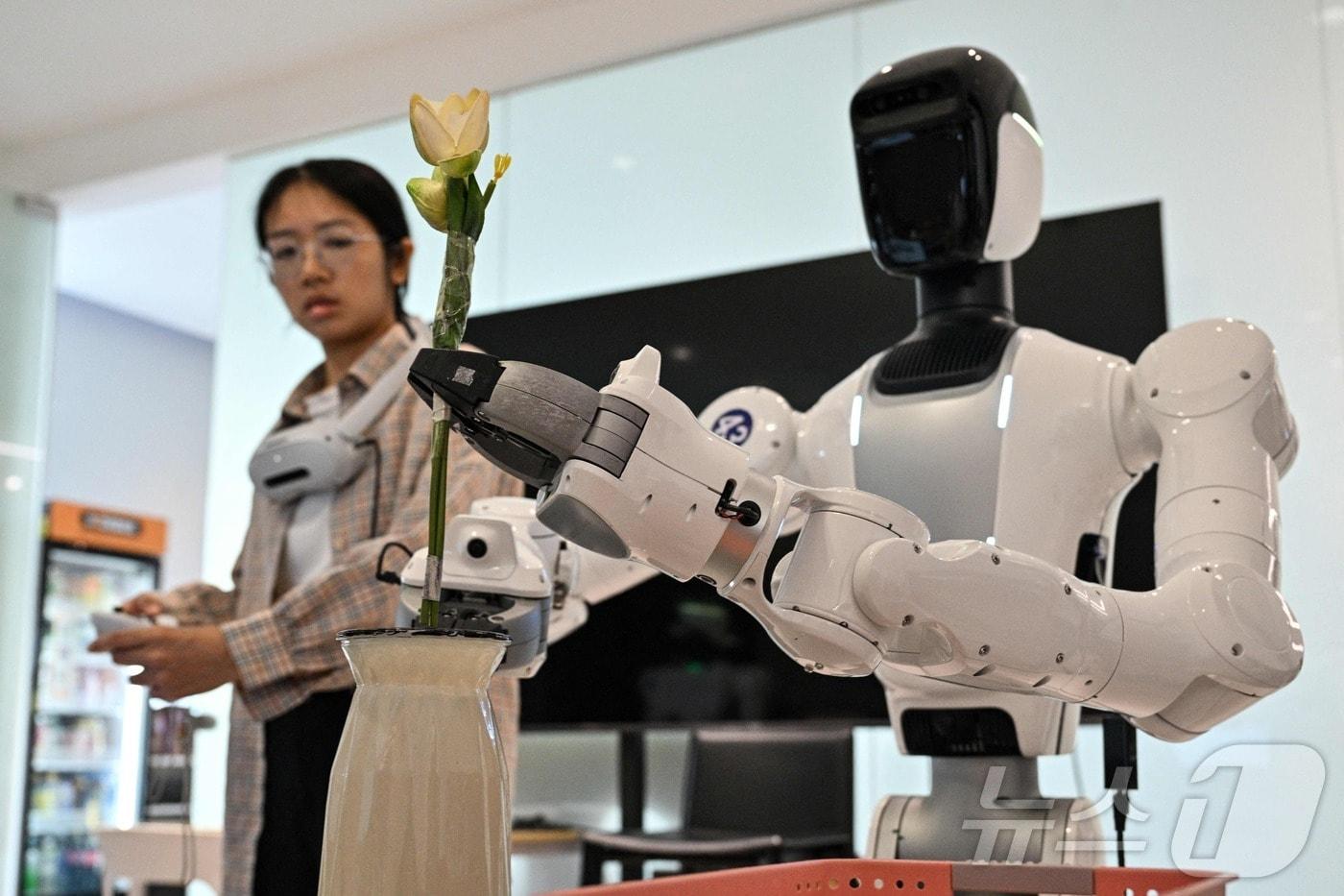 본문 이미지 - 중국 광둥성 선전의 엑스스퀘어 로봇(X Square Robot) 시설에서 2026년 5월 22일 한 엔지니어가 휴머노이드 로봇에 가사 업무 수행 동작을 학습시키고 있다. ⓒ AFP=뉴스1