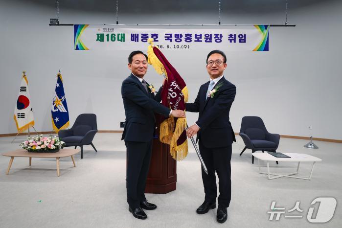 본문 이미지 - 10일 서울 용산구 국방홍보원에서 열린 16대 국방홍보원장 취임식에서  이두희 국방부 차관이 배종호 신임 원장에게 국방홍보원기를 수여하고 있다. (국방일보 제공)