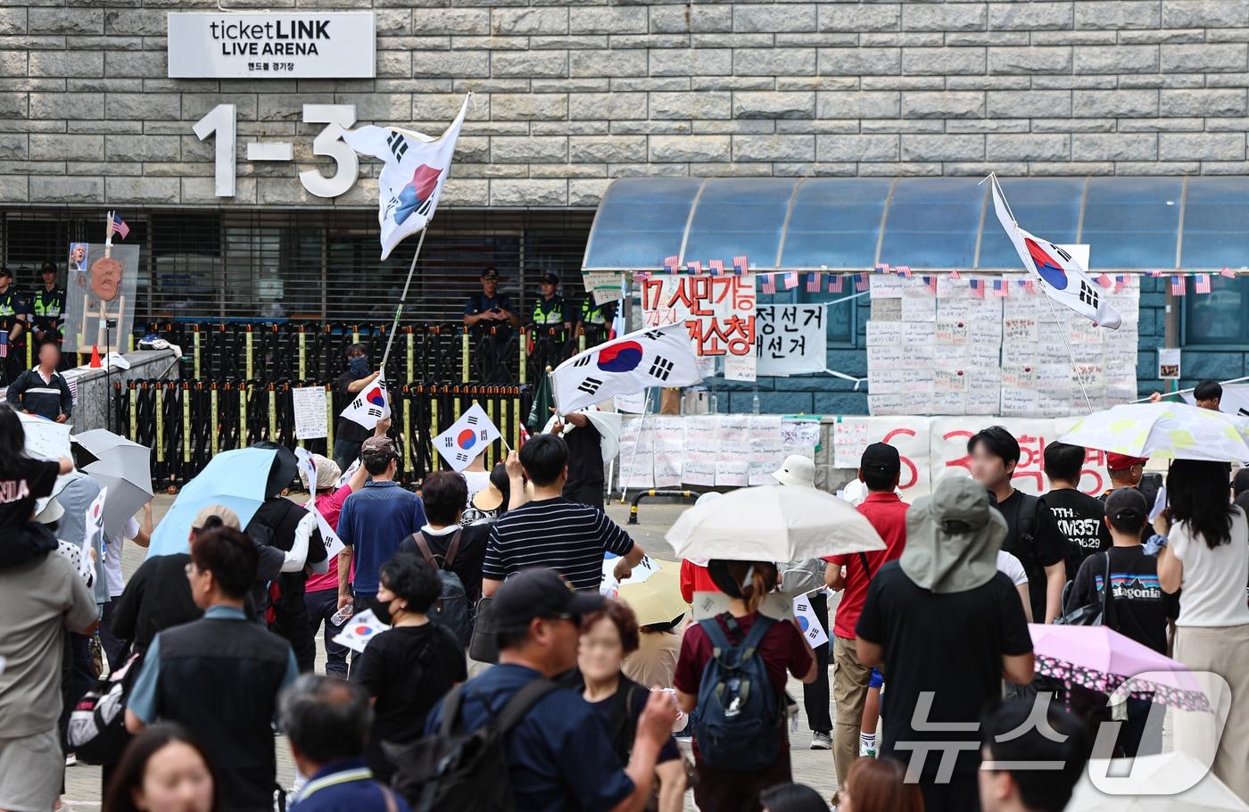 본문 이미지 - 6·3 지방선거 투표용지 부족 사태에 반발한 시민들이 14일 서울 송파구 올림픽공원 핸드볼경기장 개표소 앞에 모여 재선거를 요구하는 구호를 외치고 있다. ⓒ 뉴스1 김도우 기자