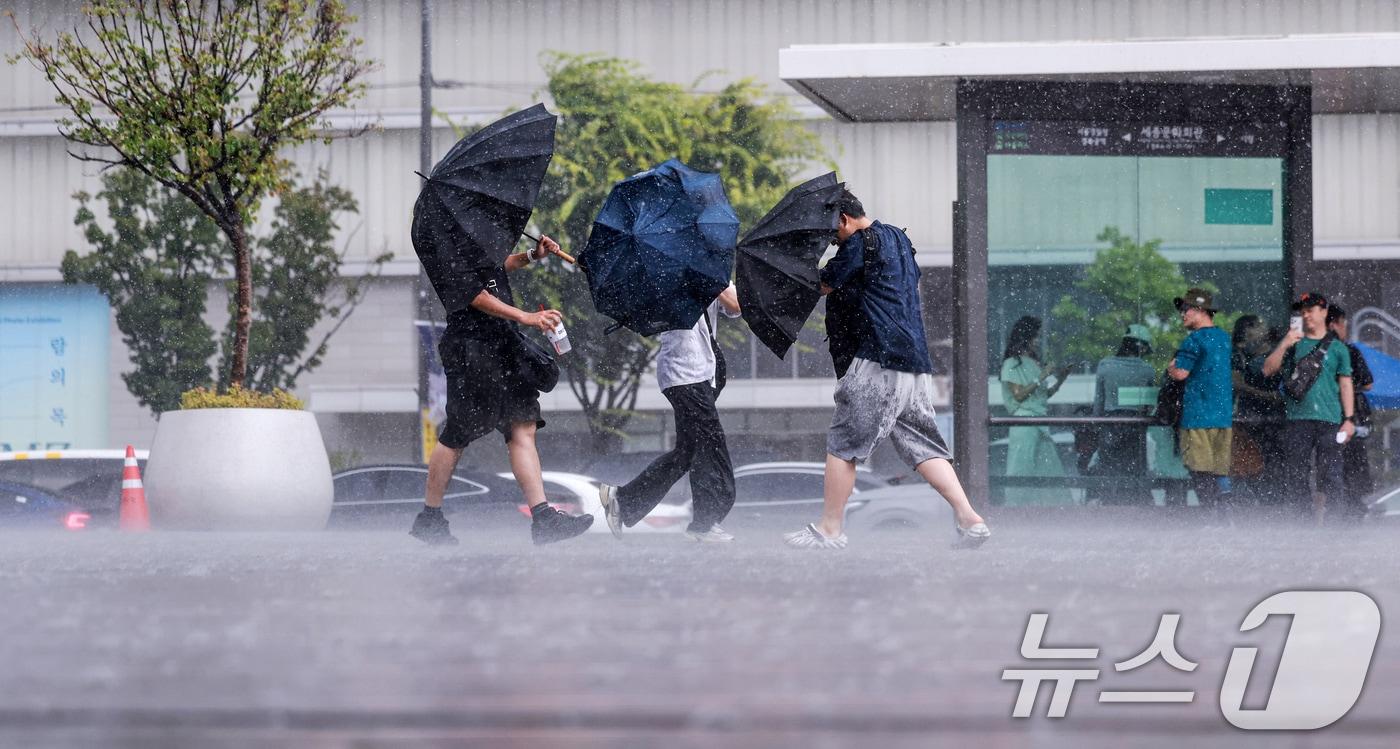 본문 이미지 - 돌풍과 벼락을 동반한 소나기가 내린 14일 서울 종로구 광화문광장에서 시민들이 우산을 쓰고 발걸음을 옮기고 있다. 2026.6.14 ⓒ 뉴스1 이호윤 기자