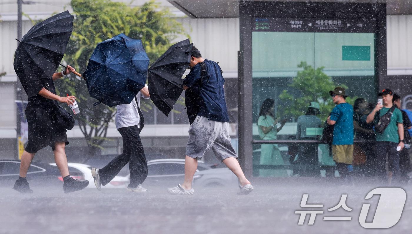 본문 이미지 - 돌풍과 벼락을 동반한 소나기가 내린  날 시민들이 우산을 쓰고 발걸음을 옮기고 있다. 2026.6.14 ⓒ 뉴스1 이호윤 기자