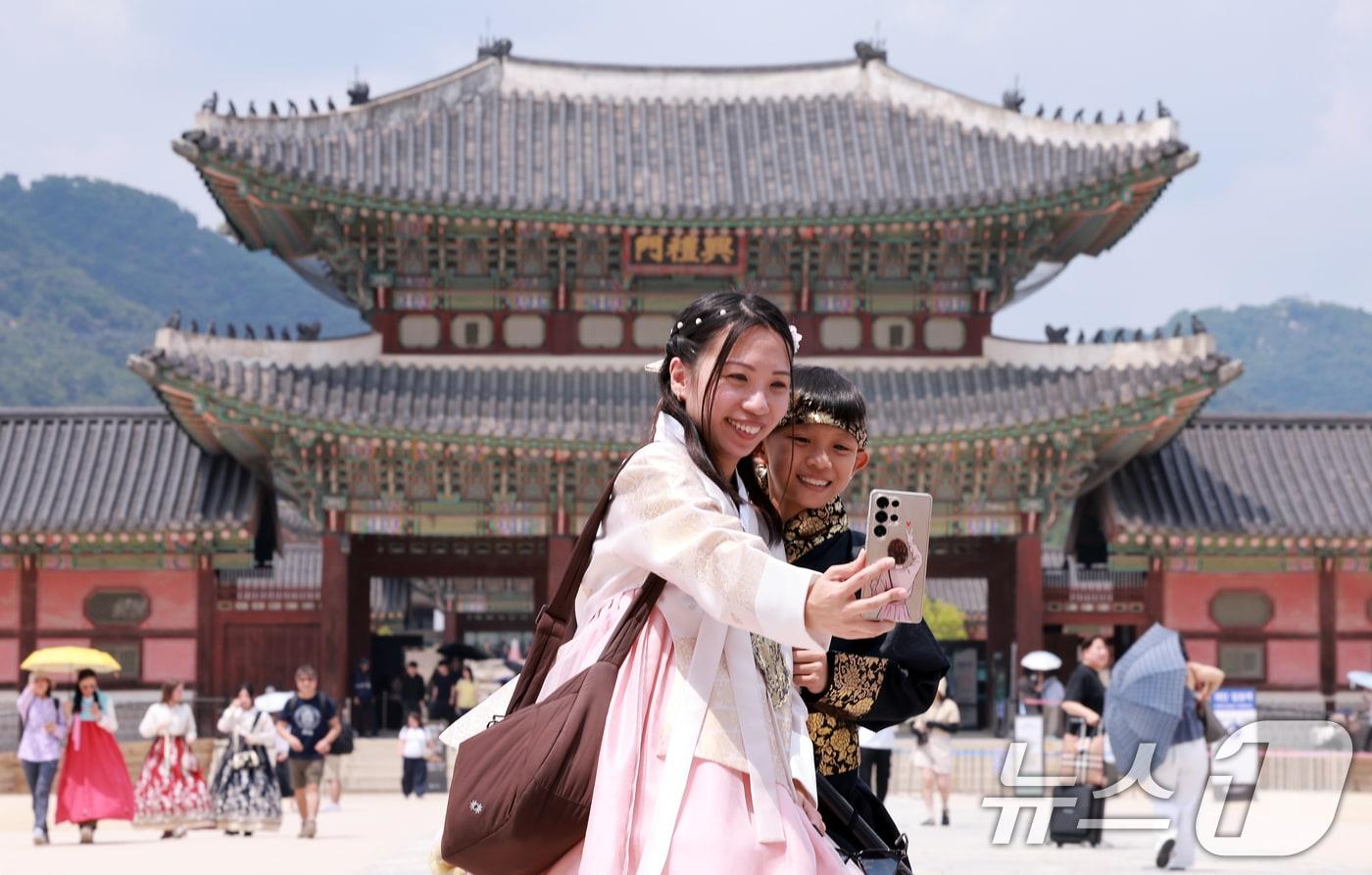 본문 이미지 - 14일 서울 종로구 경복궁에서 한복을 입은 외국인 모자가 셀카를 찍고 있다. 이날 한국문화관광연구원의 '국제관광시장 전망'에 따르면 원화 가치가 하락하면서 한국 여행 비용 부담이 줄자 외국인 관광객 급증해 올해 방한 관광객은 약 2200만명으로 전망된다. 이는 전년 대비 16.2% 증가한 수준이다. 2026.6.14 ⓒ 뉴스1 이호윤 기자