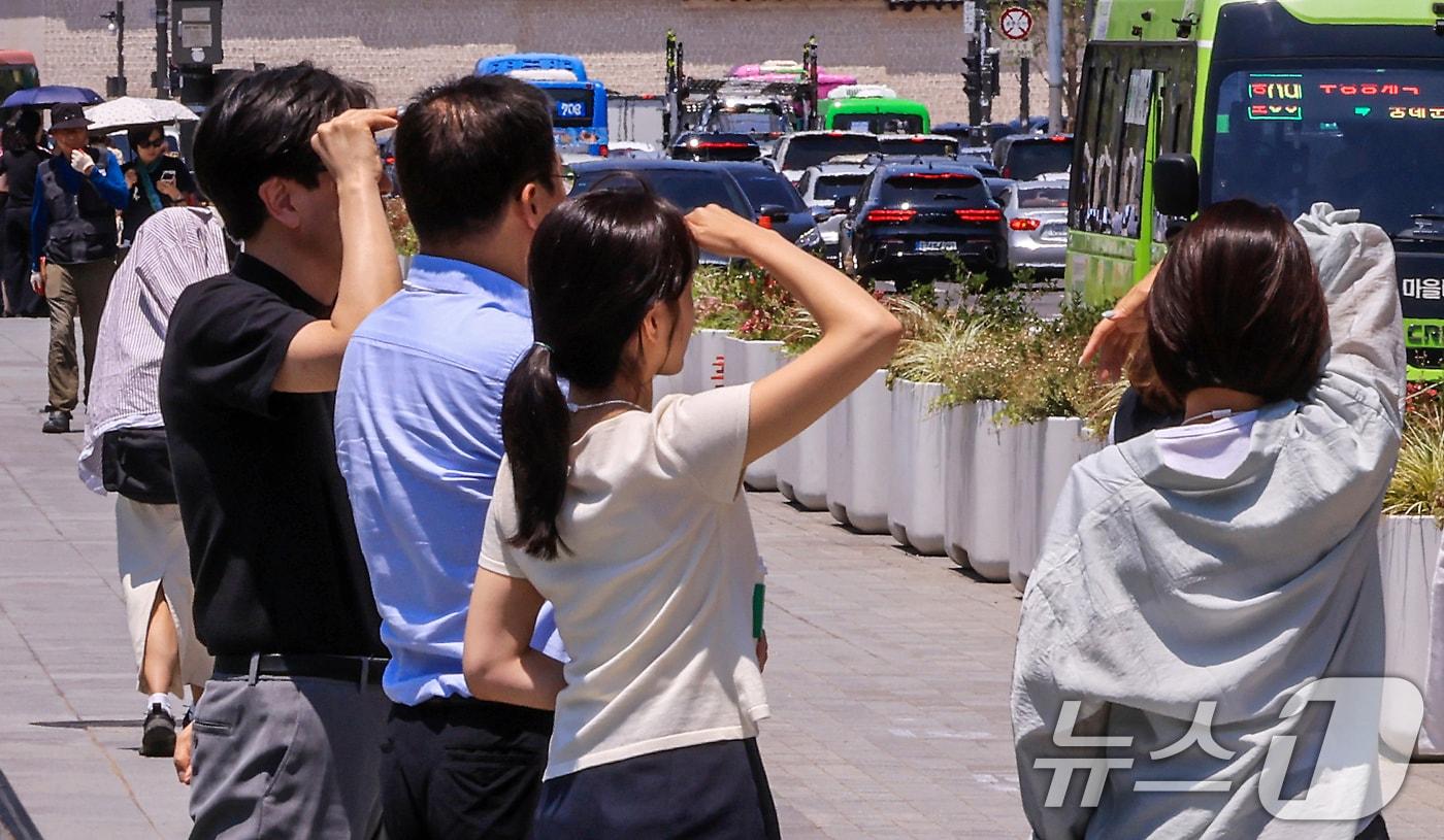 본문 이미지 - 서울 낮 최고기온이 32도까지 오르며 무더운 날씨를 보인 15일 서울 종로구 광화문광장에서 시민들이 팔로 햇빛을 가리고 있다. 2026.6.15 ⓒ 뉴스1 이호윤 기자