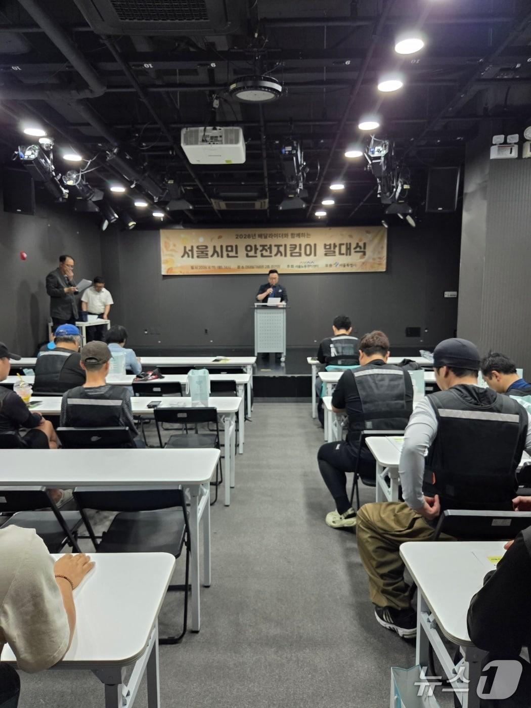 본문 이미지 - 서울시가 15일 전태일기념관에서 '2026 배달라이더 서울시민 안전지킴이' 발대식을 개최하고 기념촬영을 하고 있다.(서울시 제공)