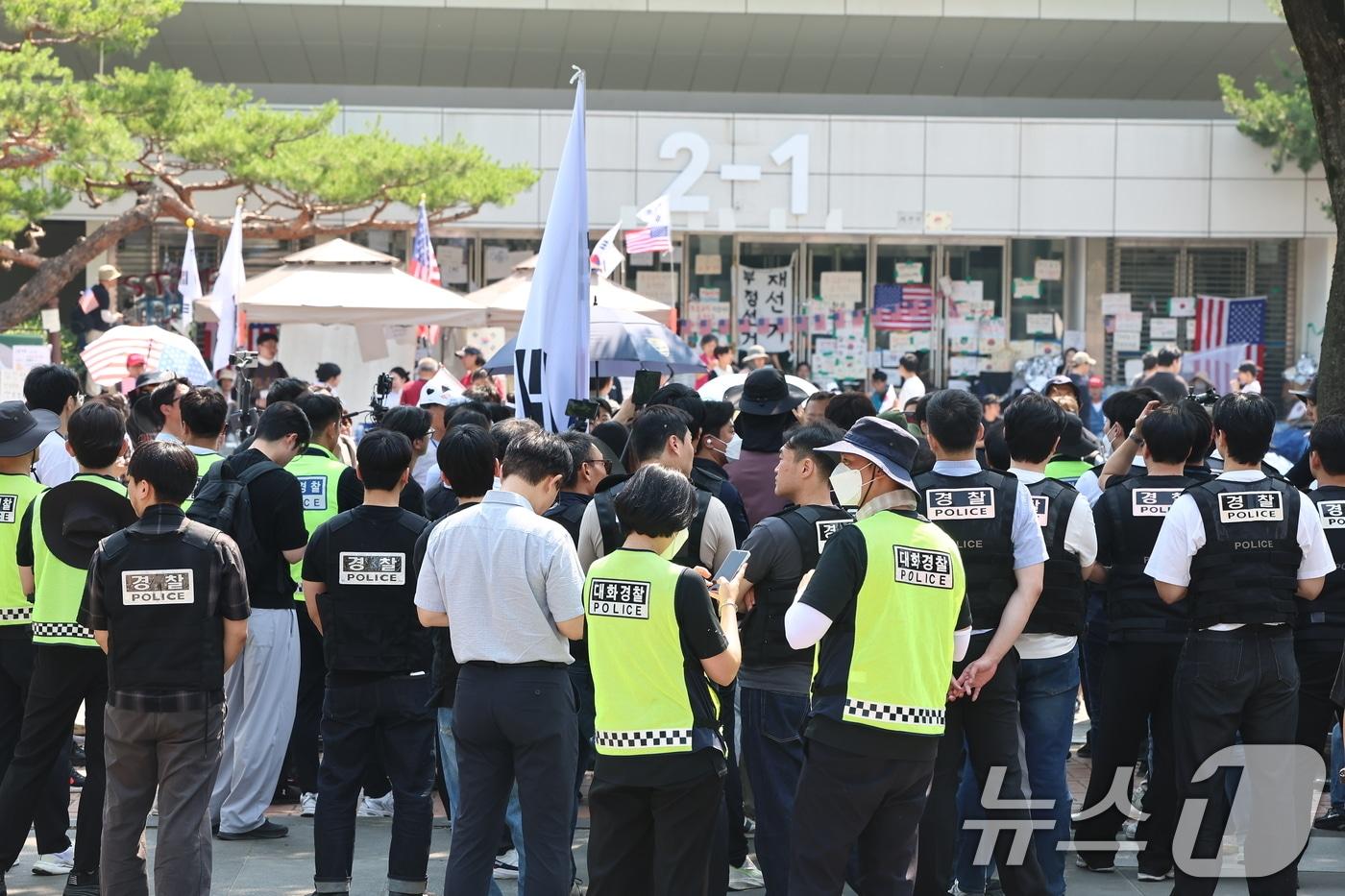 본문 이미지 - 6·3 지방선거 '투표용지 부족 사태'로 12일째 잠실 개표소 봉쇄 시위가 이어지고 있는 16일 경찰과 대한체육회 등관계자들이 서울 송파구 올림픽공원 핸드볼경기장 진입을 시도하다 시위대와 대치하고 있다. 2026.6.16 ⓒ 뉴스1 김도우 기자
