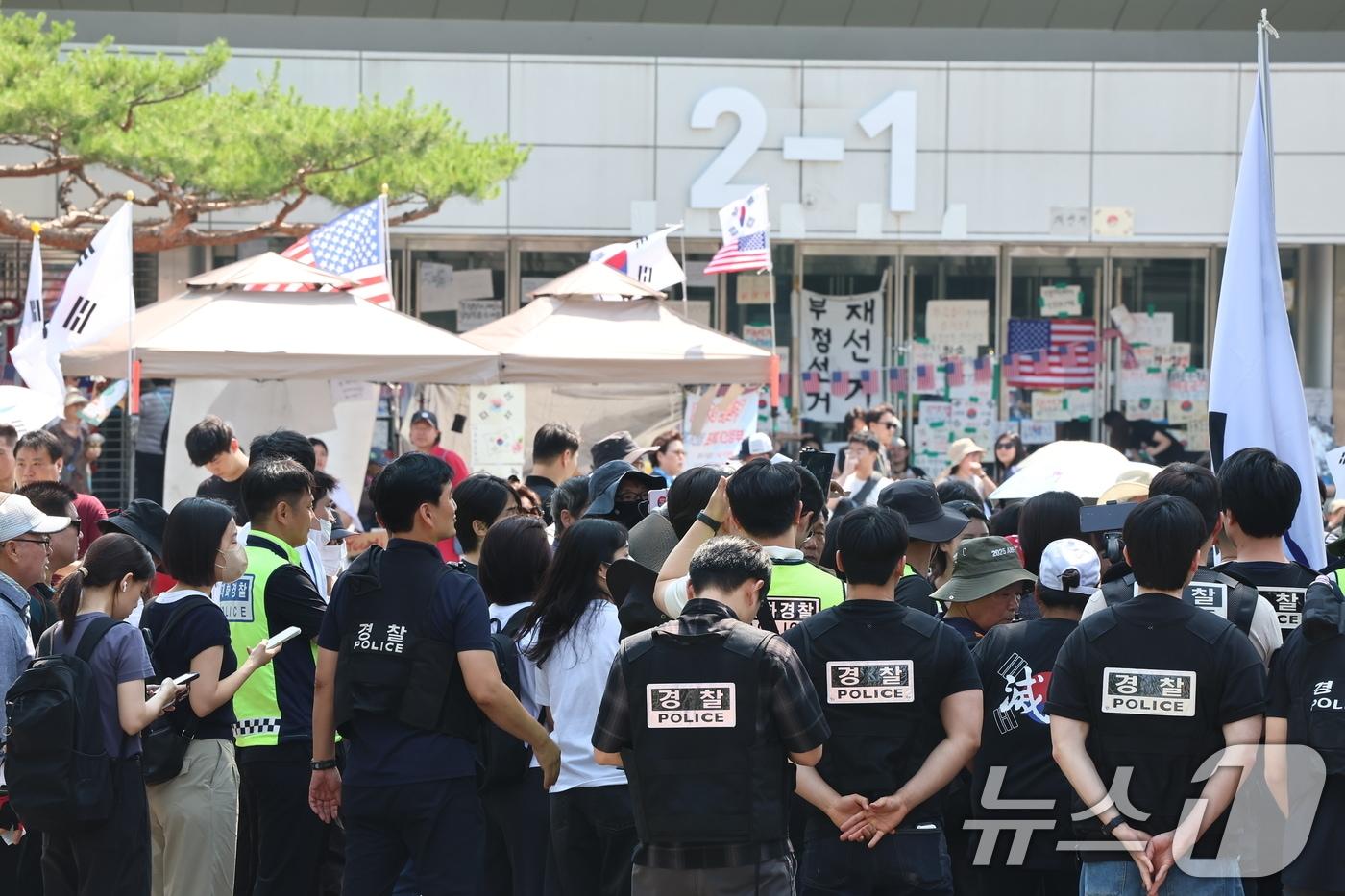 본문 이미지 - 6·3 지방선거 '투표용지 부족 사태'로 12일째 잠실 개표소 봉쇄 시위가 이어지고 있는 16일 경찰과 대한체육회 등관계자들이 서울 송파구 올림픽공원 핸드볼경기장 진입을 시도하다 시위대와 대치하고 있다. 2026.6.16 ⓒ 뉴스1 김도우 기자