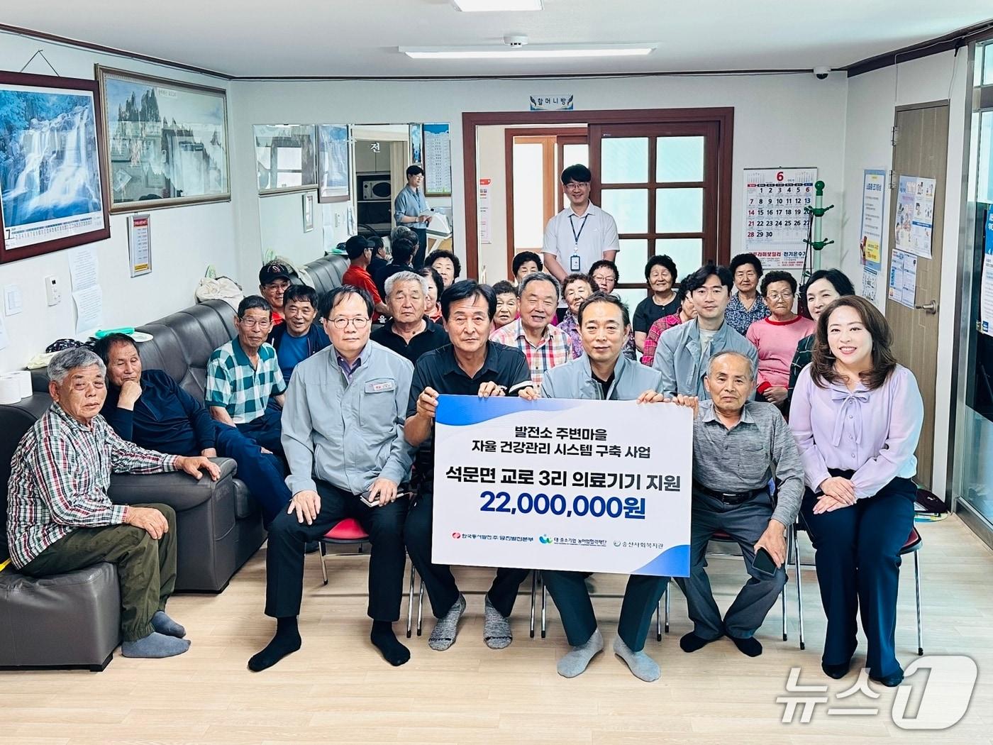 본문 이미지 - 지난 15일 당진발전본부 관계자들이 교로3리에 건강관리 의료기기를 전달하고 주민들과 기념촬영을 하고 있다.(당진발전본부 제공. 재판매 및 DB금지)2026.6.16/뉴스1