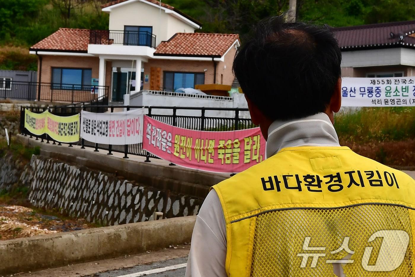 본문 이미지 - 18일 오전 경북 영덕군 영덕읍 석리 마을 주민이 마을 곳곳에 걸려있는 신규원전 유치 현수막을 지켜보고 있다. 정부는 전날 제11차 전력수급계획에 따라 신규 원전 2기를 영덕에 건설하기로 확정했다. 2026.6.18 ⓒ 뉴스1 최창호 기자