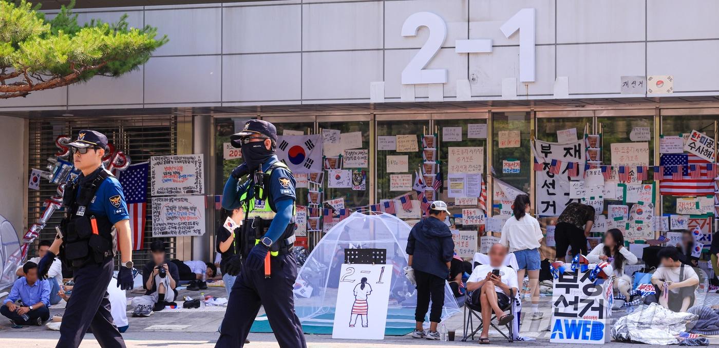 본문 이미지 - 제9회 전국동시지방선거 투표용지 부족 사태를 규탄하는 개표소 봉쇄 시위가 계속된 18일 서울 송파구 올림픽공원 핸드볼경기장 앞에서 경찰들이 이동하고 있다. 2026.6.18 ⓒ 뉴스1 이호윤 기자