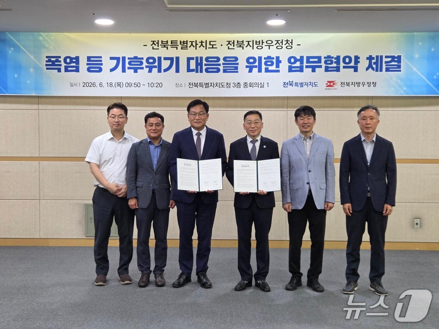 본문 이미지 - 18일 전북도청 중회의실에서 전북도와 전북지방우정청 간의 '폭염 등 기후위기 공동 대응을 위한 업무협약식'이 개최된 가운데 참석자들이 기념 촬영을 하고 있다.(전북도 제공. 재판매 및 DB금지)/뉴스1 