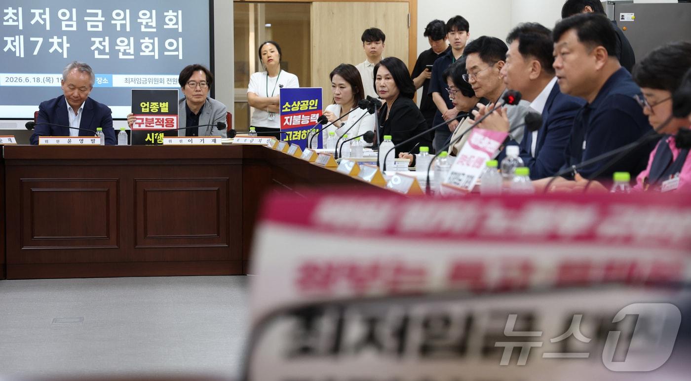 본문 이미지 - 18일 세종시 정부세종청사 최저임금위원회에서 열린 2027년도 최저임금위원회 7차 전원회의에 참석한 사용자위원과 근로자위원들이 각자의 주장이 적힌 손팻말을 게시하며 발언을 듣고 있다. 2026.6.18 ⓒ 뉴스1 김기남 기자