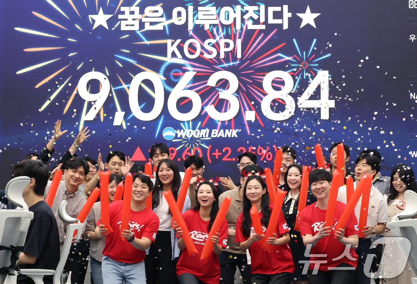 본문 이미지 - 코스피 지수가 전인미답의 9000선 고지를 돌파한 18일 오후 서울 중구 우리은행 본점 딜링룸에서 직원들이 코스피 종가를 배경으로 축하 세리머니를 하고 있다. 코스피는 이날 전일 대비 199.60포인트(2.25%) 오른 9063.84에 장을 마쳤다. 한국 증시는 반도체 대형주의 폭발적인 상승세에 힘입어 지난 5월 26일 장중 8000선을 돌파한 후 불과 16거래일 만에 천의 자리를 바꾸며 '9천피' 시대에 진입했다. ⓒ 뉴스1 오대일 기자