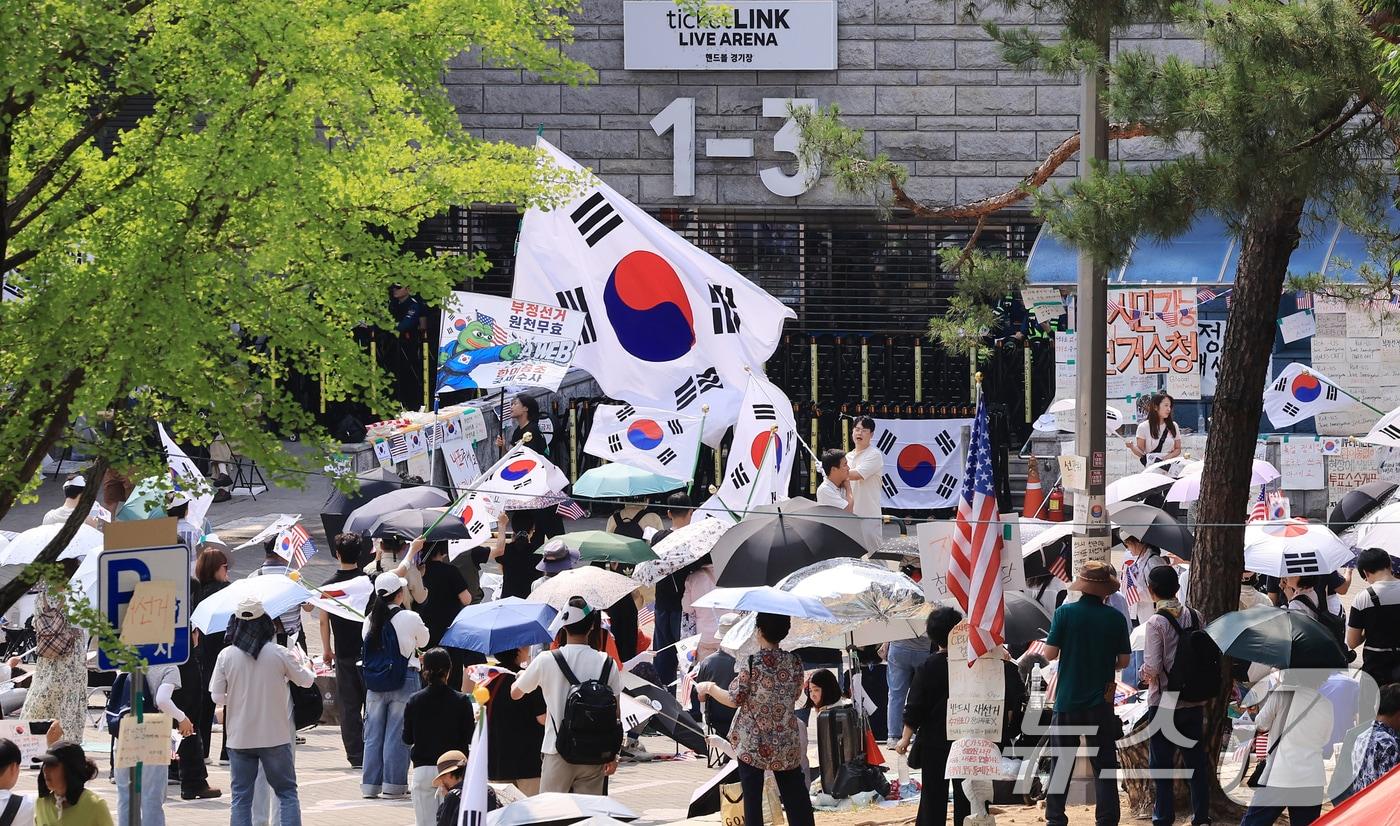본문 이미지 - 제9회 전국동시지방선거 투표용지 부족 사태를 규탄하는 개표소 봉쇄 시위가 계속된 18일 서울 송파구 올림픽공원 핸드볼경기장 앞에서 시민들이 구호를 외치고 있다. 2026.6.18 ⓒ 뉴스1 이호윤 기자