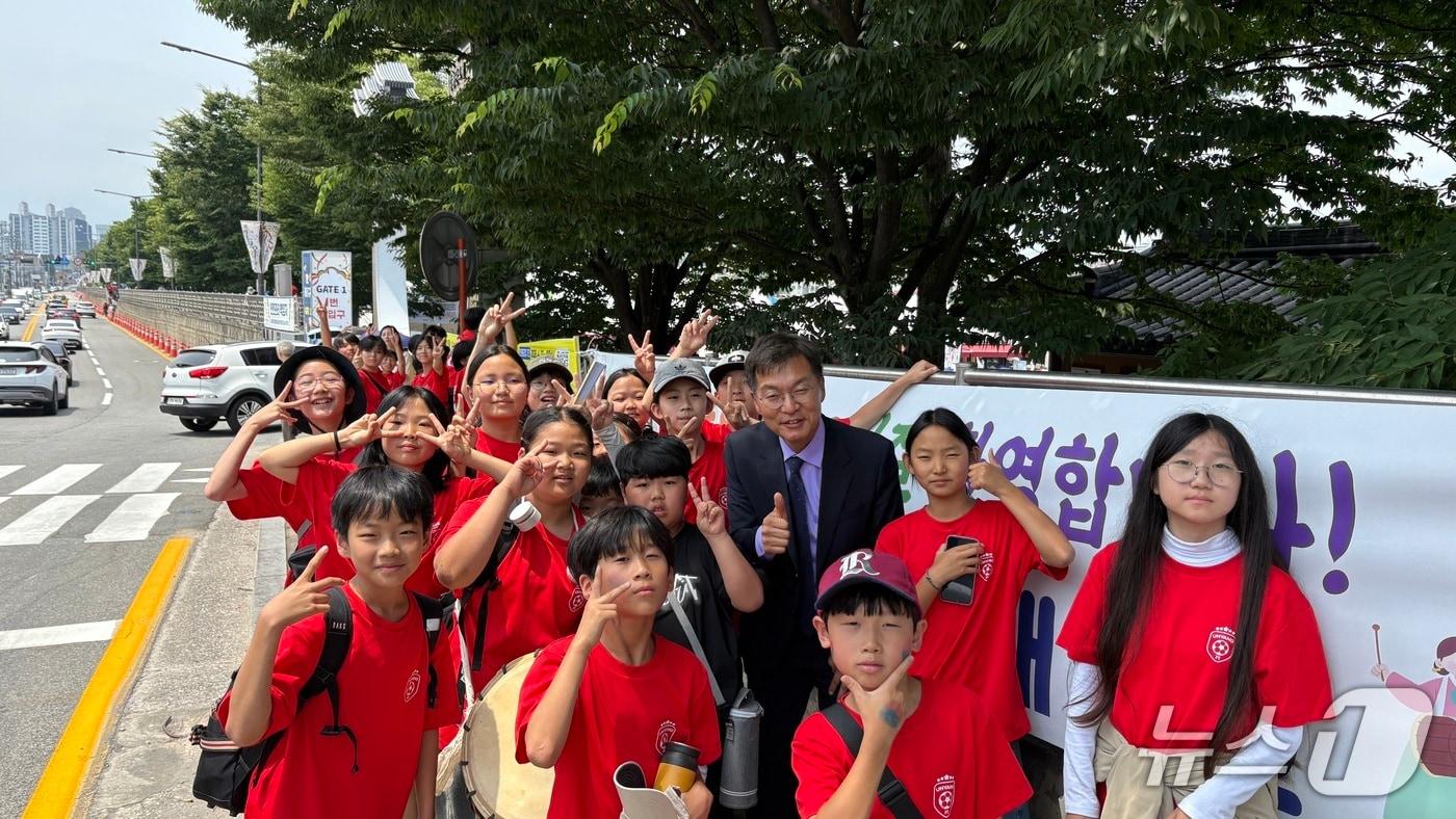 본문 이미지 - 김중남 민선 9기 강원 강릉시장 당선인이 2026 북중미 월드컵 한국과 멕시코의 조별리그 두번째 경기가 열린 19일 오전 강릉단오제 수리마당에서 운양초 학생들과 응원전을 펼친 뒤 기념촬영을 하고 있다.(강릉시장직 인수위원회 제공, 재판매 및 DB 금지) 2026.6.19/뉴스1