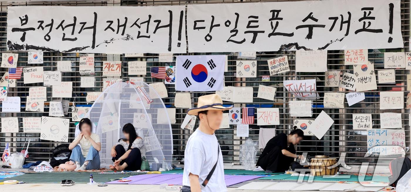 본문 이미지 - 제9회 전국동시지방선거 투표용지 부족 사태를 규탄하는 개표소 봉쇄 시위가 계속된 22일 서울 송파구 올림픽공원 핸드볼경기장 개표소 출입구에 재선거를 요구하는 메시지가 붙어 있다. 2026.6.22 ⓒ 뉴스1 이호윤 기자