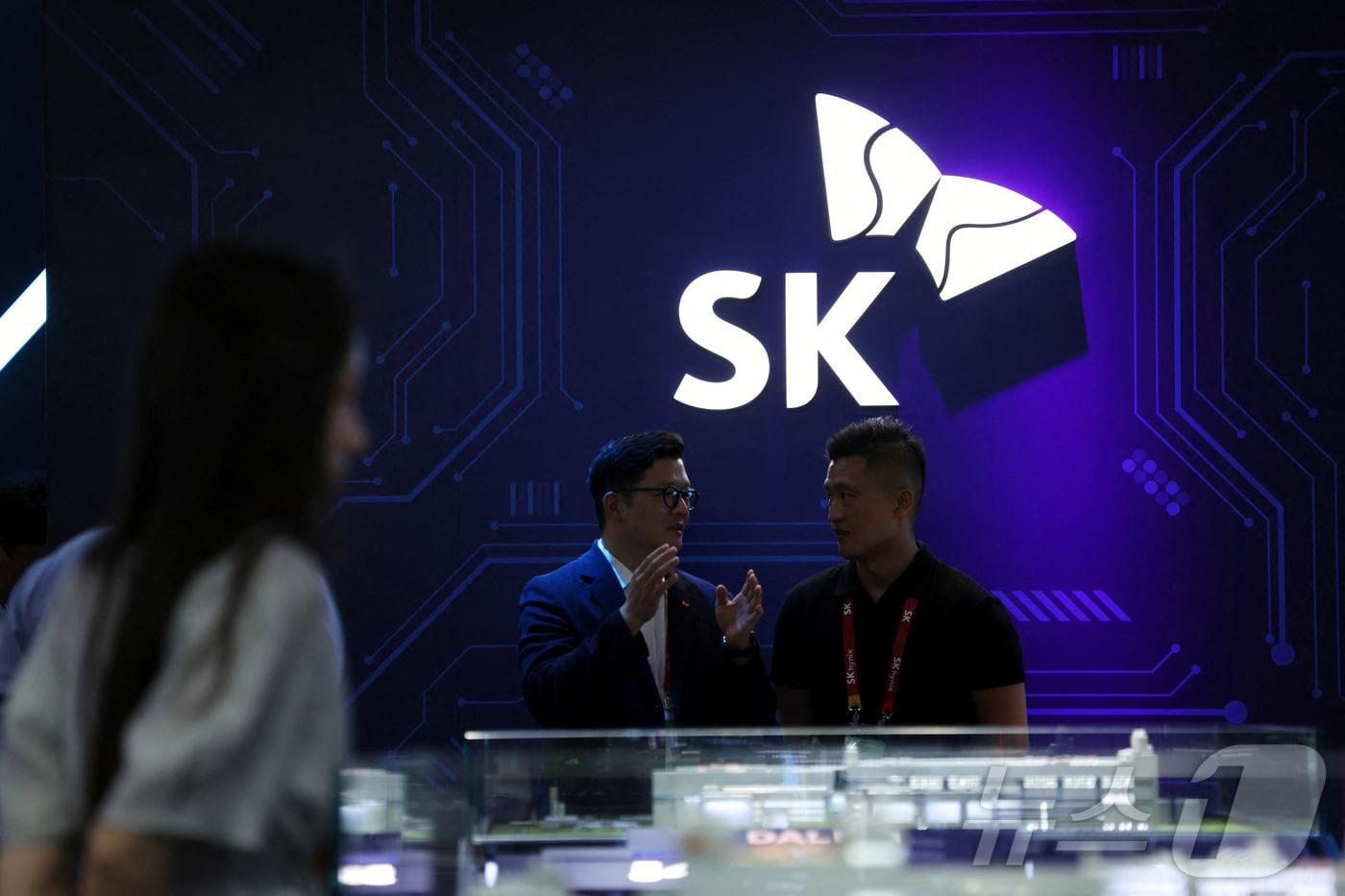 본문 이미지 - People stand near a logo of SK Hynix at the South Korean chipmaker's booth during the China International Supply Chain Expo (CISCE) in Beijing, China June 22, 2026. REUTERS/Florence Lo ⓒ 로이터=뉴스1