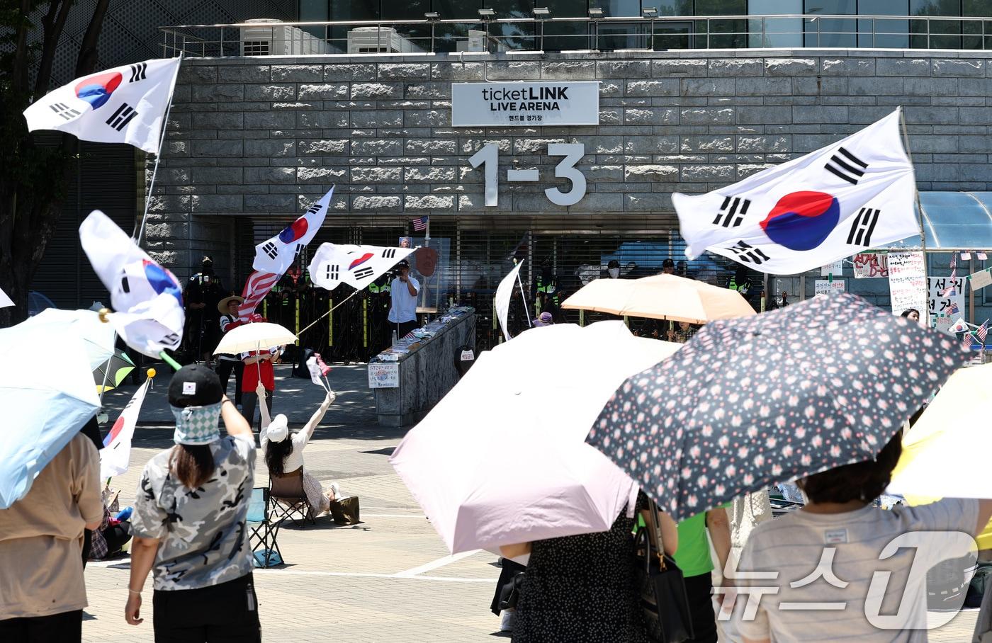 본문 이미지 - 제9회 전국동시지방선거 투표용지 부족 사태를 규탄하는 개표소 봉쇄 시위가 이어지는 23일 서울 송파구 올림픽공원 핸드볼경기장 개표소 앞에서 집회 참가자들이 구호를 외치고 있다. 2026.6.23 ⓒ 뉴스1 최지환 기자
