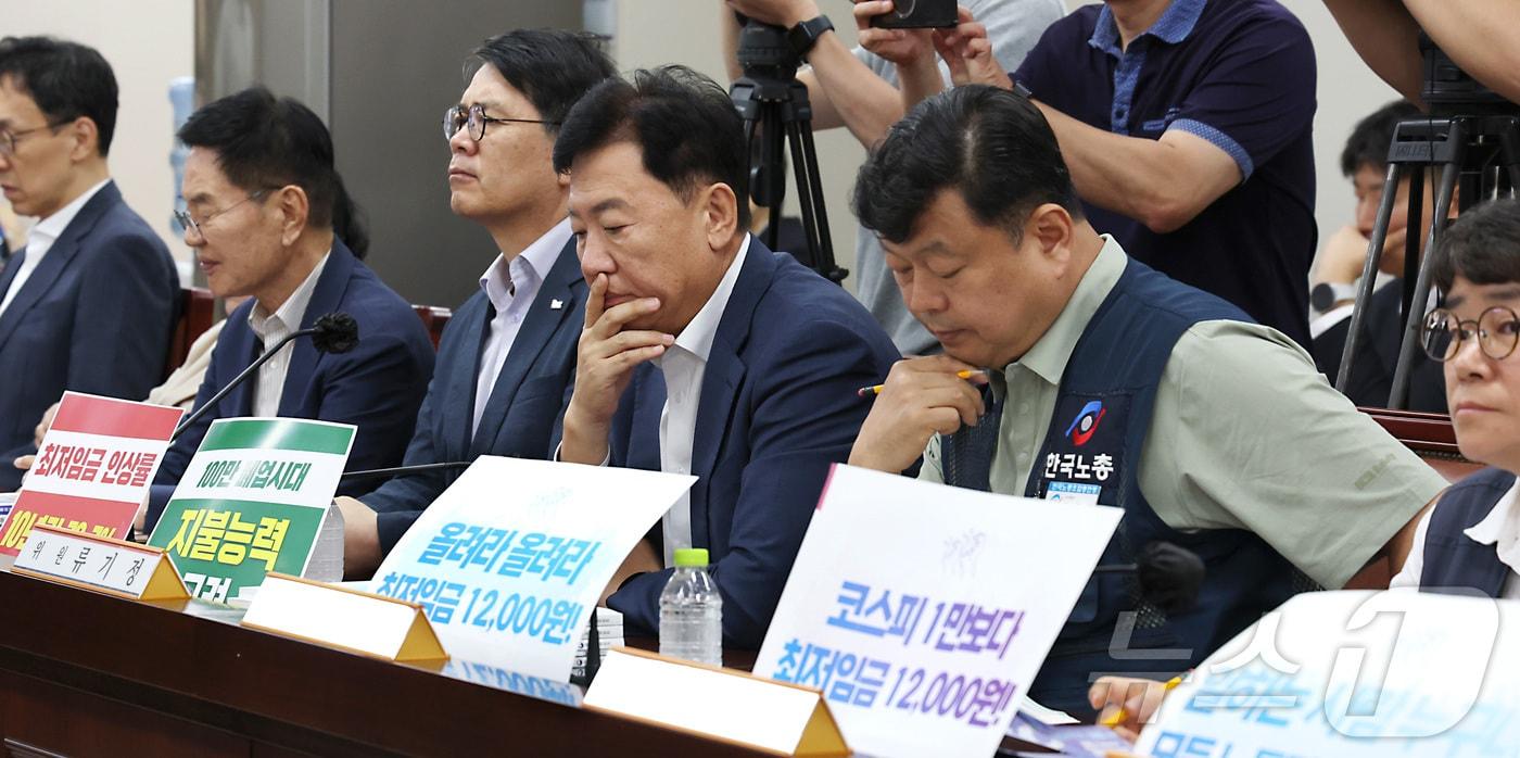 본문 이미지 - 류기정 사용자위원과 류기섭 근로자위원이 23일 세종시 정부세종청사 최저임금위원회에서 열린 2027년도 최저임금위원회 8차 전원회의에서 최저임금 1만2000원 요구와 지불능력 고려 손팻말을 게시하고 본격적인 논의를 시작하고 있다. (사진은 기사 내용과 무관함) 2026.6.23 ⓒ 뉴스1 자료 사진