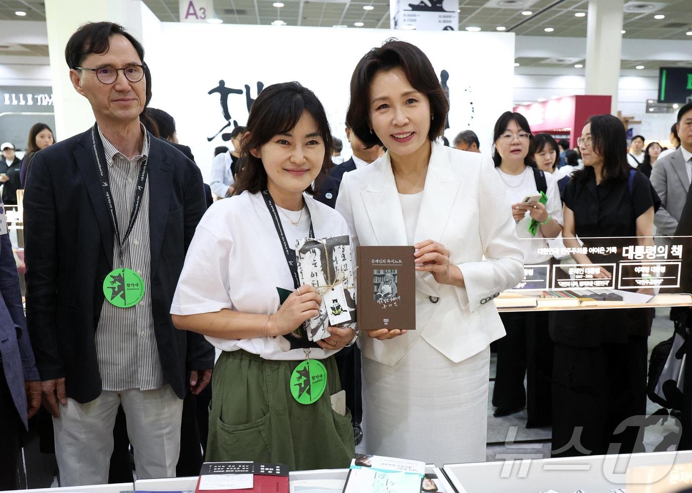 본문 이미지 - 김혜경 여사가 24일 서울 강남구 코엑스에서 열린 2026 서울국제도서전 개막식에서 문재인 전 대통령의 저서 '문재인의 독서노트'를 들고 기념촬영을 하고 있다. 2026.6.24 ⓒ 뉴스1 허경 기자