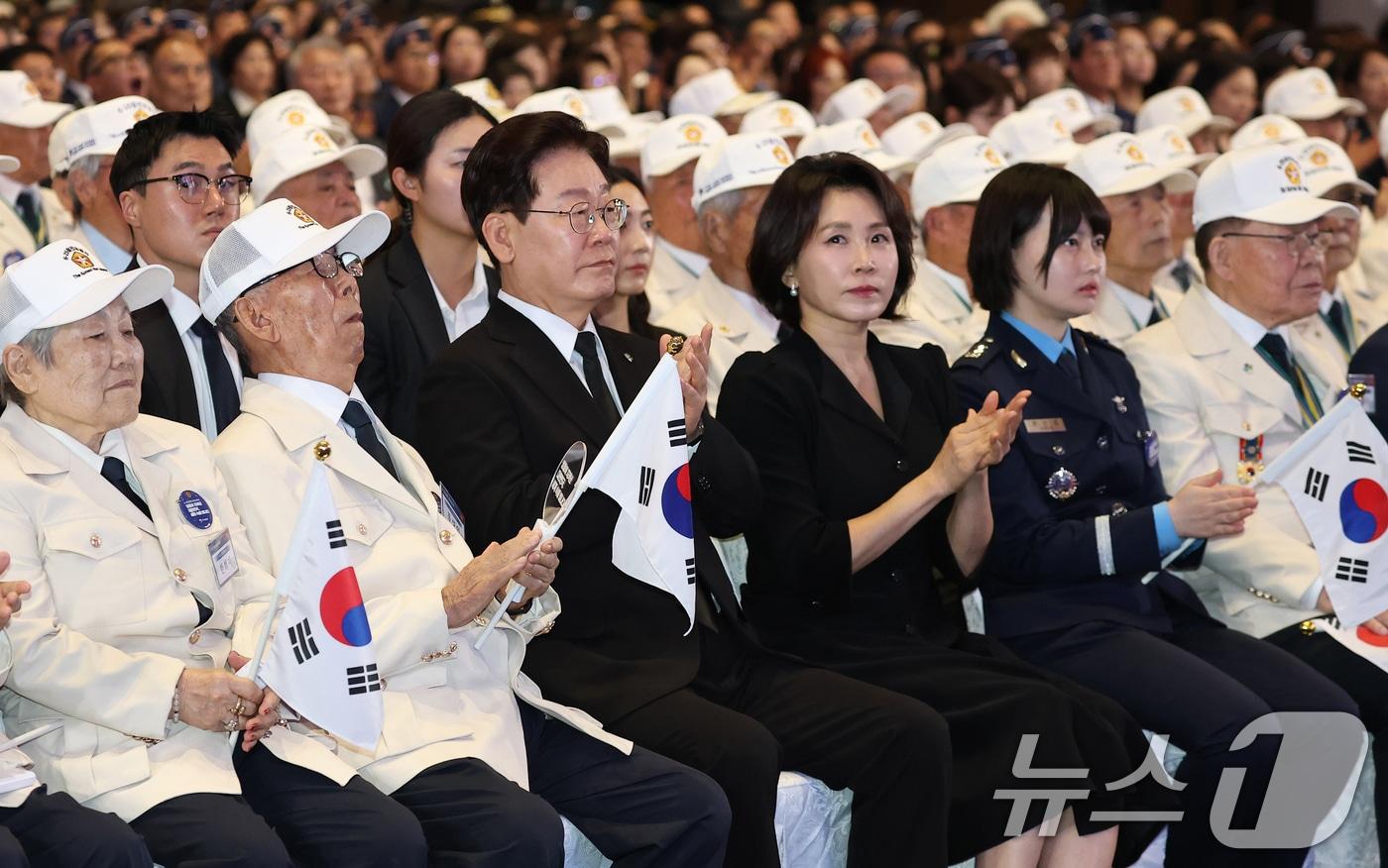 본문 이미지 - 이재명 대통령과 김혜경 여사가 25일 경기 수원시 영통구 수원컨벤션센터에서 열린 6·25 전쟁 제76주년 기념식에서 참전국 국기 입장에 빅수를 치고 인사하고 있다. (청와대통신사진기자단) 2026.6.25 ⓒ 뉴스1 허경 기자