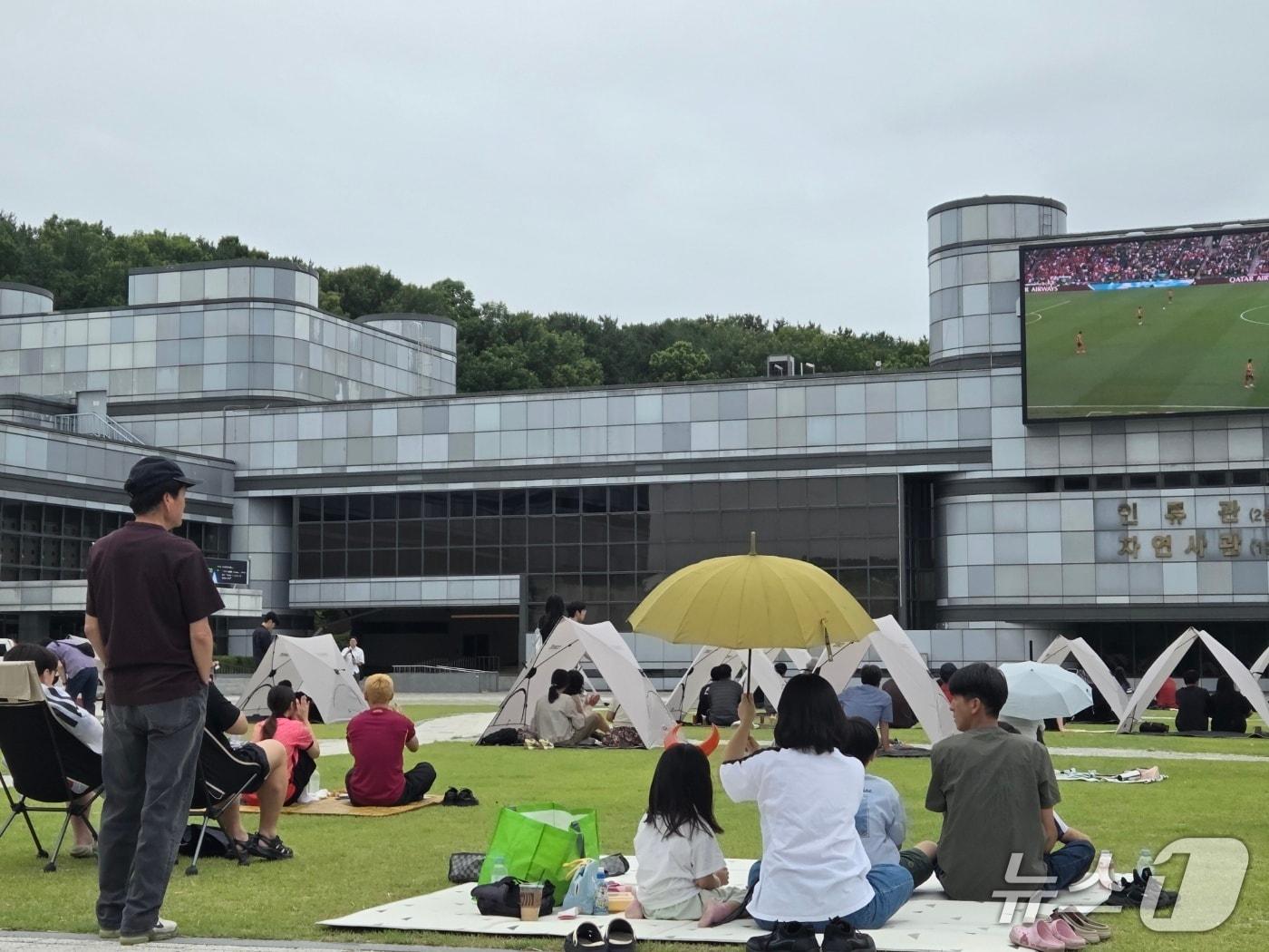 본문 이미지 - 2026북중미 월드컵 한국과 남아프리카공화국의 조별리그 마지막 경기가 열린 26일 오전 국립중앙과학관 꿈이광장에서 시민들이 경기를 관람하고 있다. ⓒ 뉴스1 김종서 기자