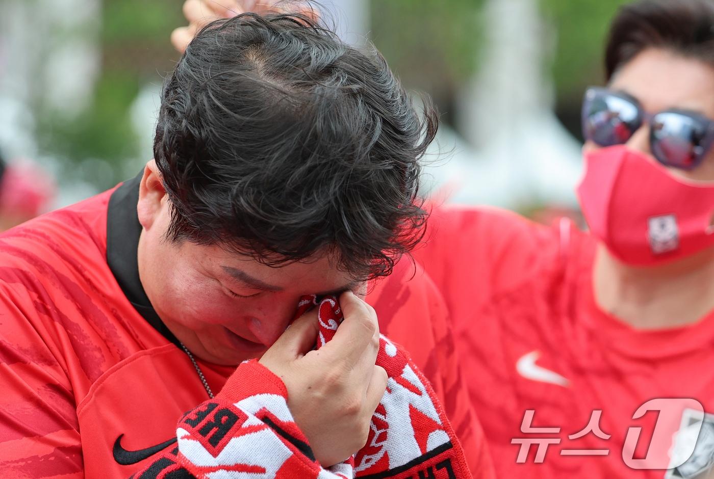 본문 이미지 - 축구 국가대표팀 공식 서포터즈 붉은악마가 25일 서울 종로구 광화문광장에서 열린 2026 국제축구연맹(FIFA) 북중미월드컵 A조 조별리그 3차전 대한민국과 남아프리카공화국의 경기 거리응원에서 0-1로 패하자 눈물을 흘리고 있다. 2026.6.25 ⓒ 뉴스1 오대일 기자