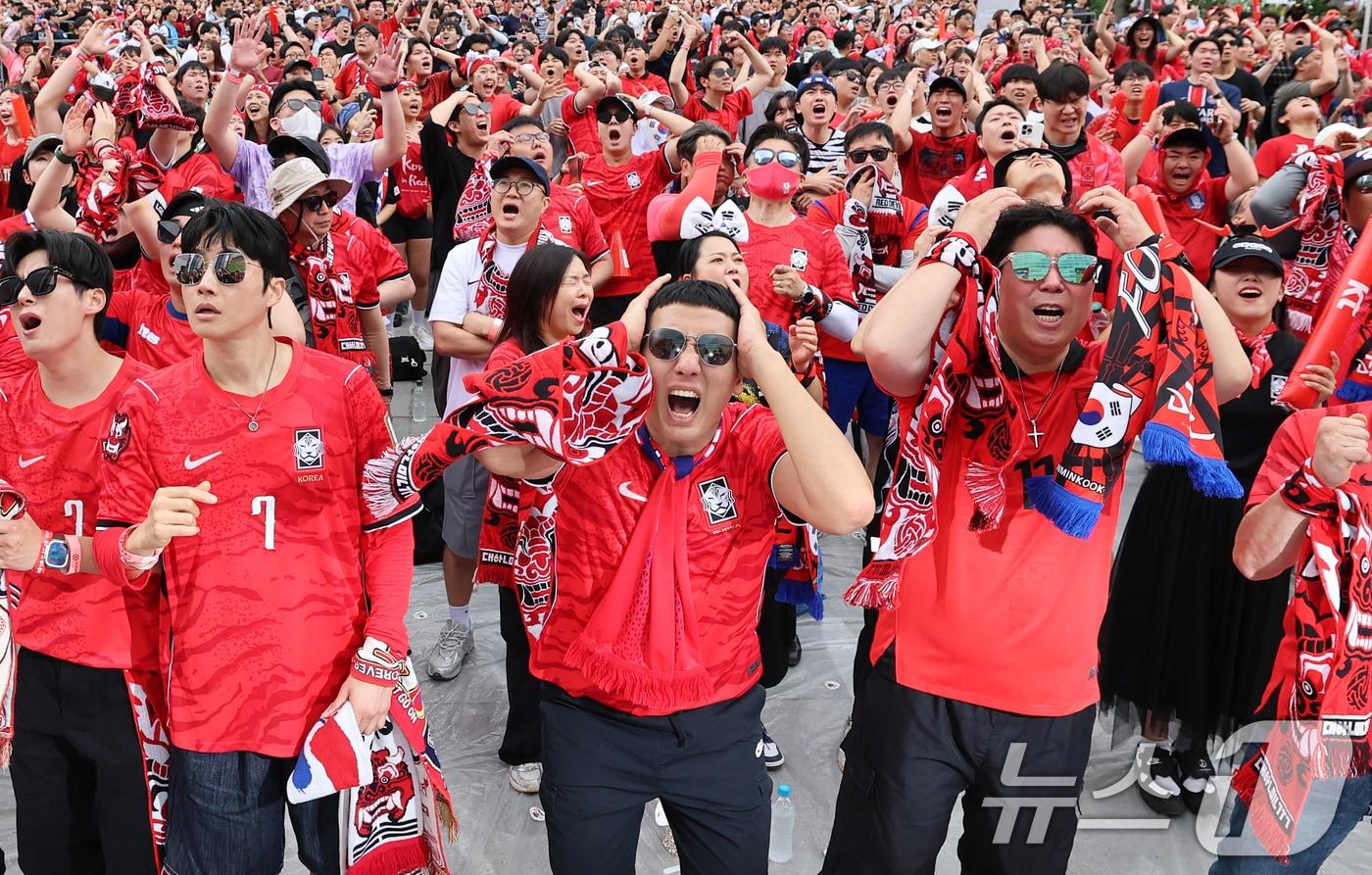 본문 이미지 - 축구 국가대표팀 공식 서포터즈 붉은악마와 시민들이 지난 25일 서울 종로구 광화문광장에서 열린 2026 국제축구연맹(FIFA) 북중미월드컵 A조 조별리그 3차전 대한민국과 남아프리카공화국의 경기 거리응원에서 머리를 감싸고 있다. 2026.6.25 ⓒ 뉴스1 오대일 기자