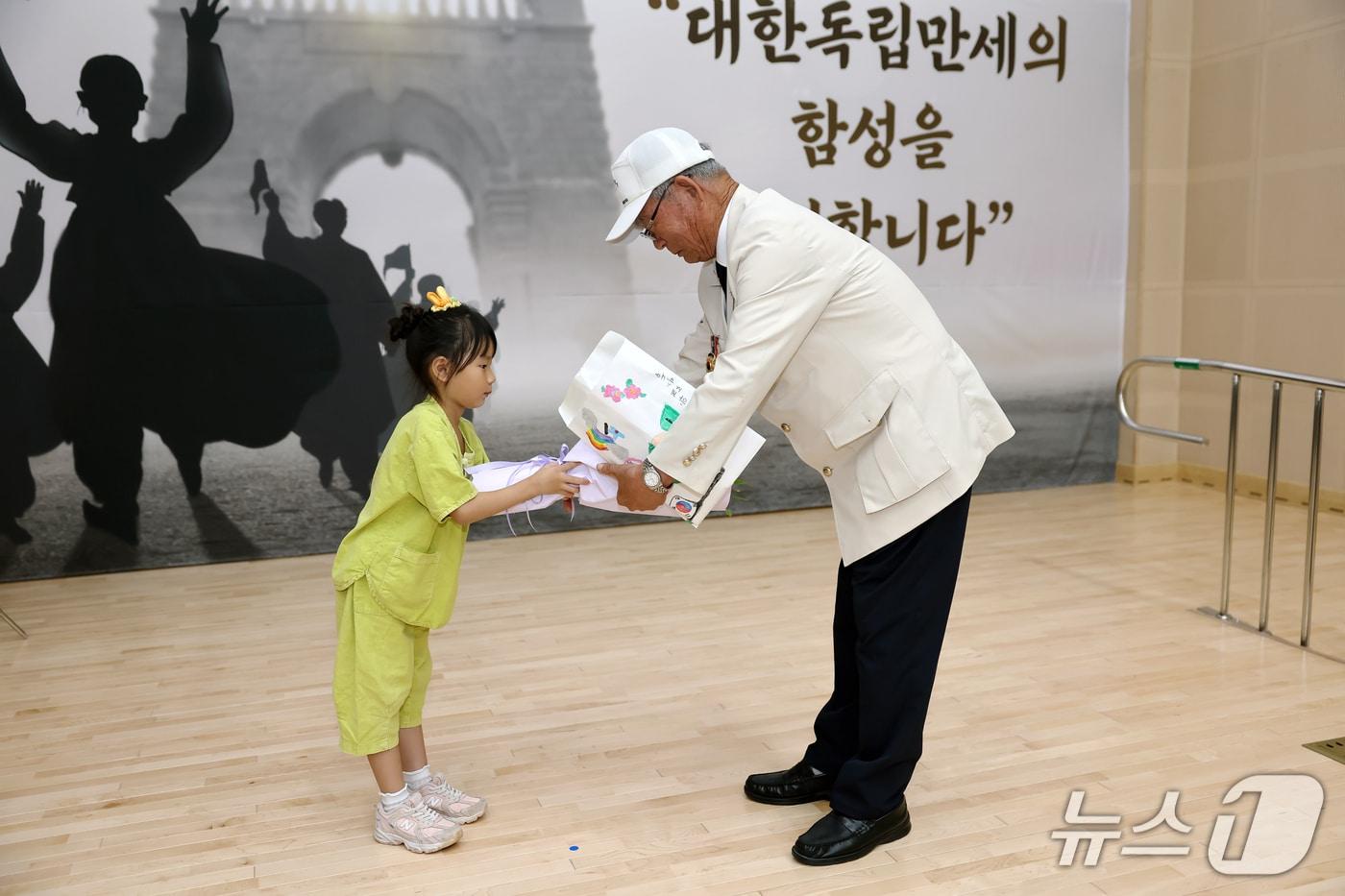 본문 이미지 - 고창보듬이나눔이어린이집 원아가 참전용사에게 감사 편지와 꽃을 전달하고 있다.(고창군 제공. 재판매 및 DB금지)