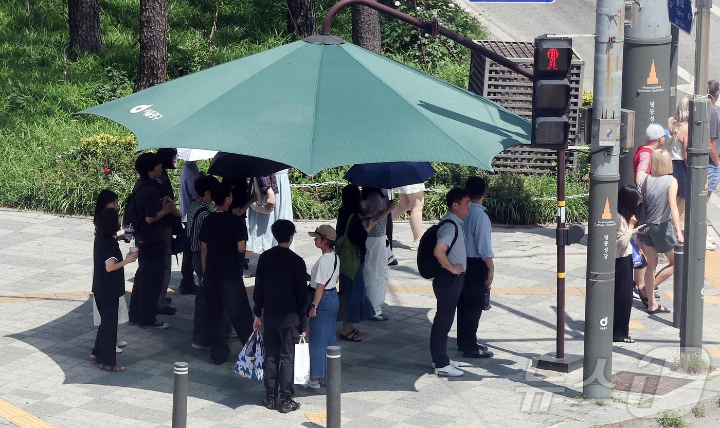 본문 이미지 - 낮 최고 기온이 30도 가까이 오르며 무더운 날씨를 보인 26일 서울 중구 을지로입구역 사거리에서 시민들이 횡단보도 앞 그늘막 아래 모여 신호를 기다리고 있다. 2026.6.26 ⓒ 뉴스1 김진환 기자