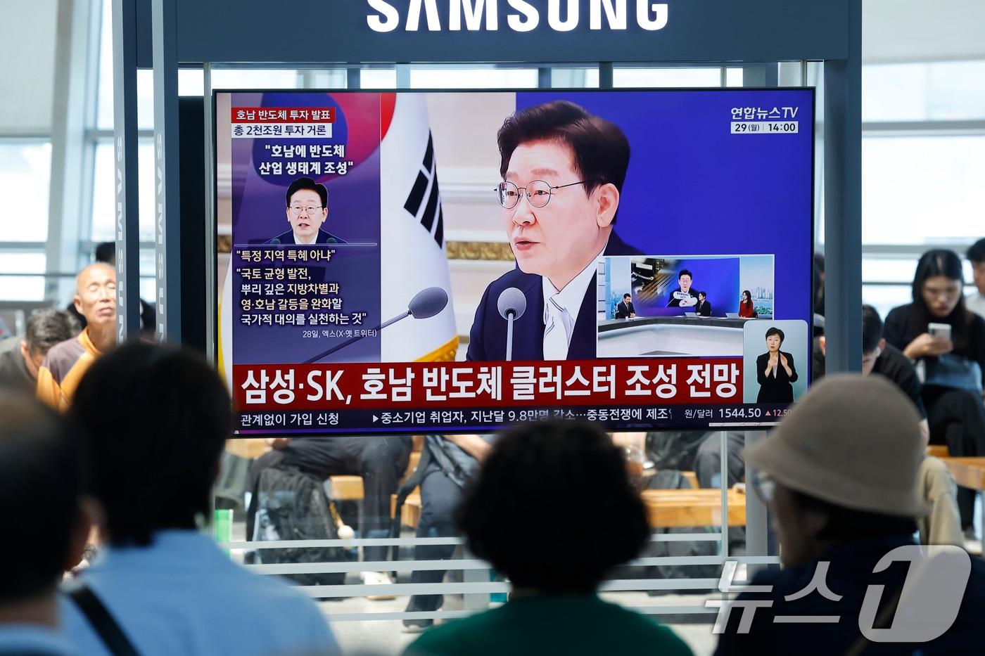 본문 이미지 - 광주 시민들이 29일 광주 KTX송정역에서 청와대 영빈관에서 열린 '대한민국 대도약 3대 메가프로젝트 국민보고회'의 이재명 대통령의 투자 발표 생중계 뉴스를 지켜보고 있다. 2026.6.29 ⓒ 뉴스1 김태성 기자