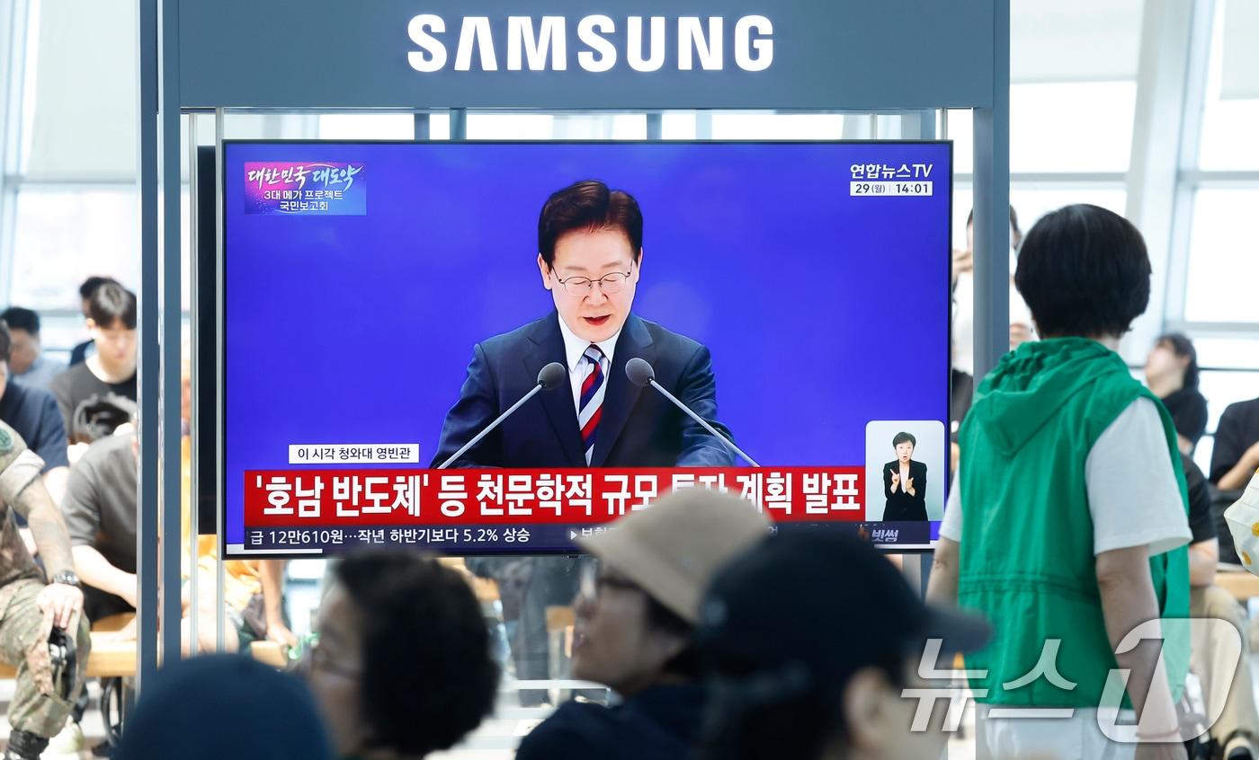 본문 이미지 - 광주 시민들이 29일 광주 KTX송정역에서 청와대 영빈관에서 열린 '대한민국 대도약 3대 메가프로젝트 국민보고회'의 이재명 대통령의 투자 발표 생중계 뉴스를 지켜보고 있다. 2026.6.29 ⓒ 뉴스1 김태성 기자