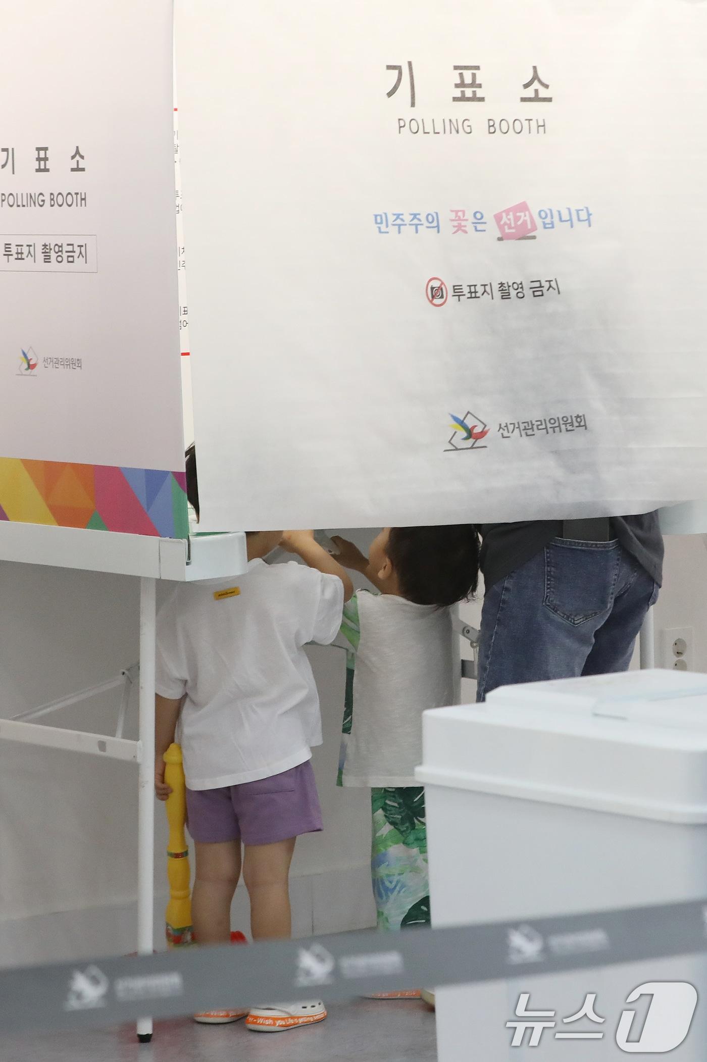본문 이미지 - 제9회 전국동시지방선거 및 국회의원 재·보궐선거일인 3일 부산 부산진구청에 마련된 부암제1동제4투표소에서 아이들이 엄마가 투표하는 모습을 지켜보고 있다. 2026.6.3 ⓒ 뉴스1 윤일지 기자