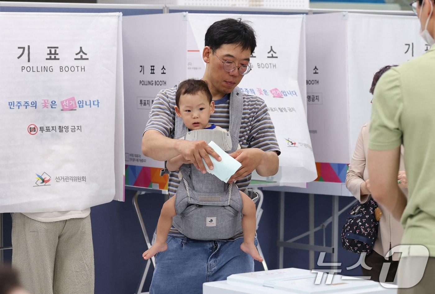 본문 이미지 - 제9회 전국동시지방선거일인 3일 서울 강남구 강남구청에 마련된 삼성2동 제5투표소에서 한 시민이 아기를 아기띠에 안은 채 소중한 한 표를 행사하고 있다. 2026.6.3 ⓒ 뉴스1 박지혜 기자