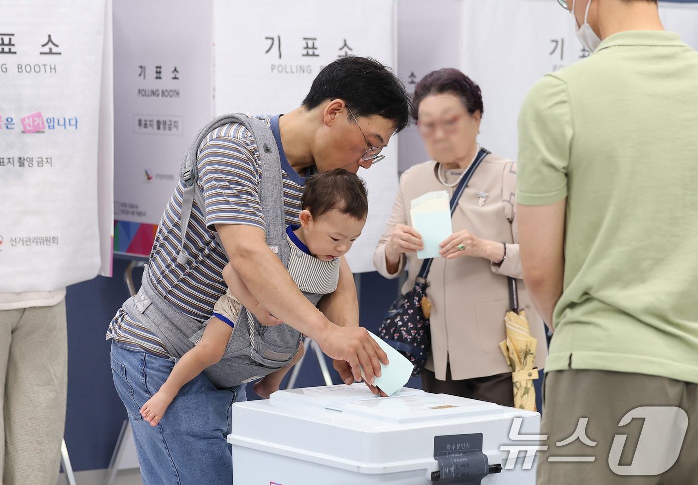 본문 이미지 - 제9회 전국동시지방선거일인 3일 서울 강남구 강남구청에 마련된 삼성2동 제5투표소에서 한 시민이 아기를 아기띠에 안은 채 소중한 한 표를 행사하고 있다. 2026.6.3 ⓒ 뉴스1 박지혜 기자