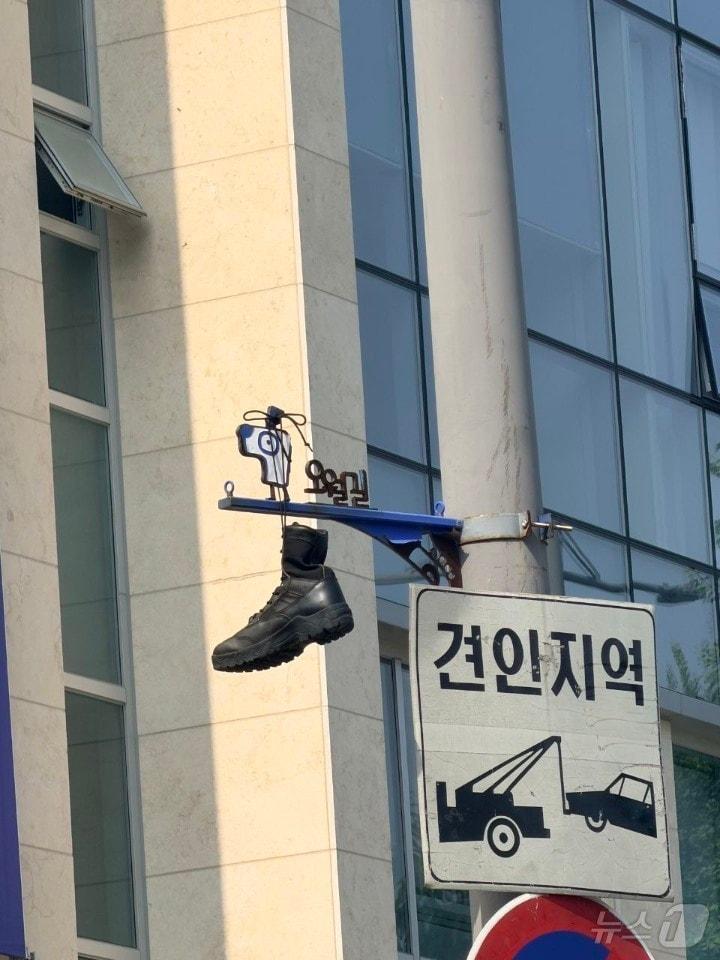 본문 이미지 - 30일 광주 동구 대인동의 한 교차로에 설치된 오월길을 안내하는 표지판에 군화가 걸려 있다. 5.18기념재단과 광주시는 군화를 수거하는 한편 누가, 어떤 의도로 군화를 걸었는지 조사에 착수했다. (5·18기념재단 제공. 재판매 및 DB금지) 2026.6.30 ⓒ 뉴스1