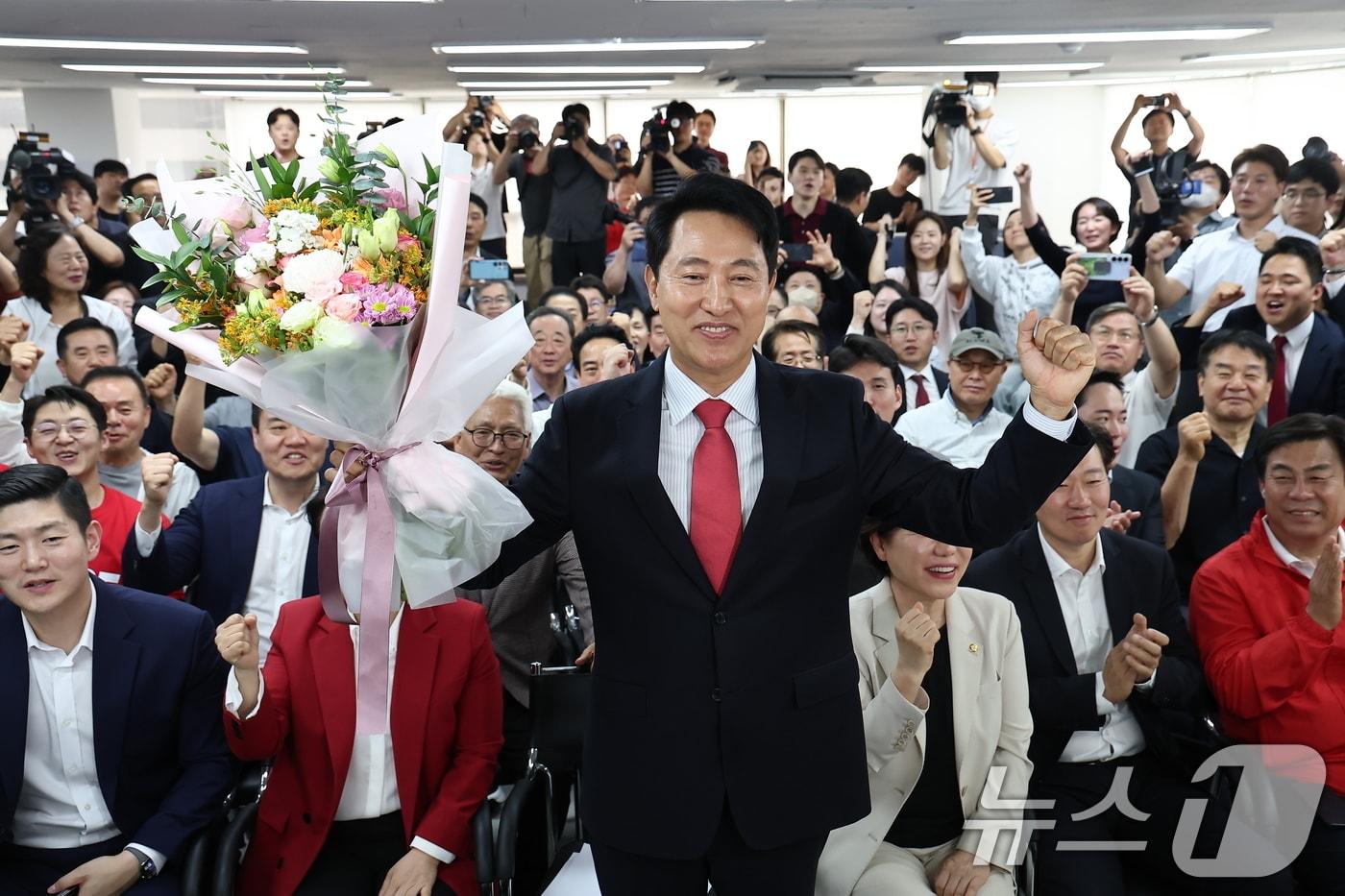 본문 이미지 - 오세훈 국민의힘 서울시장 후보가 4일 서울 종로구에 마련된 본인의 선거사무소에서 당선이 유력해지자 입장 발표 후 꽃다발을 받고 환호 있다. 2026.6.4 ⓒ 뉴스1 김도우 기자