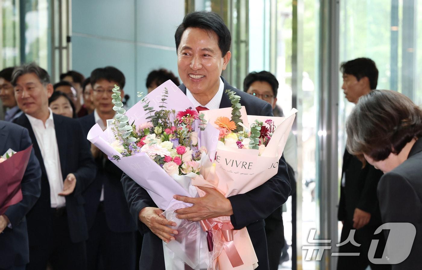 본문 이미지 - 오세훈 서울시장 당선인이 4일 오전 서울시청 로비에서 직원들이 준비해 준 꽃다발을 받고 기뻐하고 있다. (공동취재) 2026.6.4 ⓒ 뉴스1 이호윤 기자