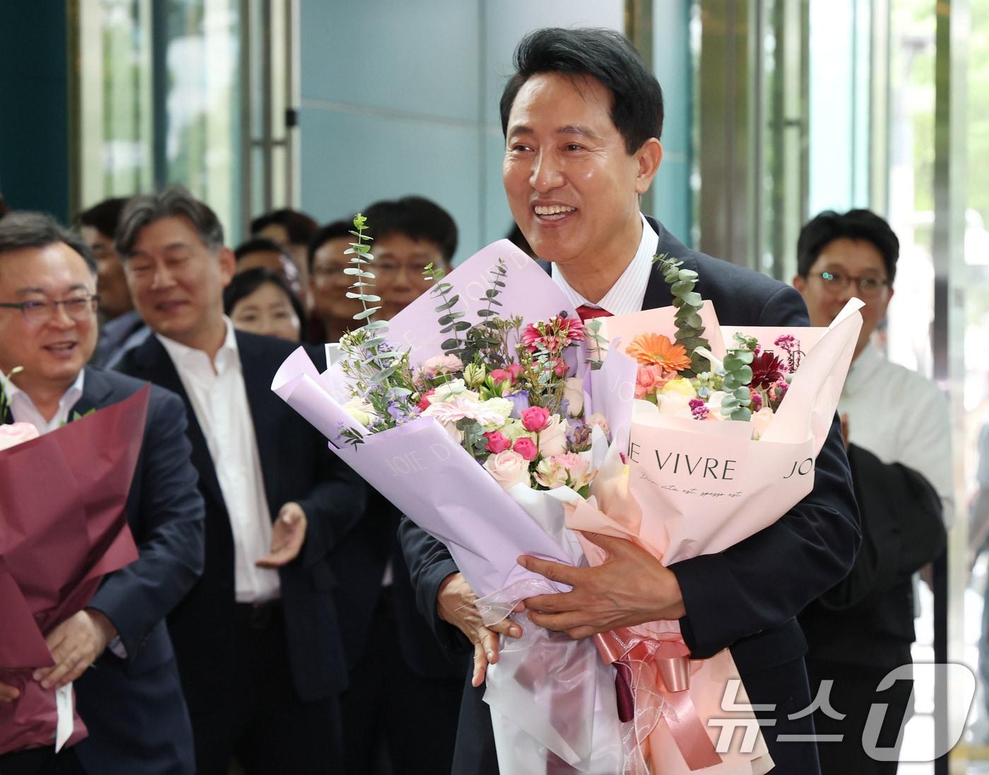 본문 이미지 - 오세훈 서울시장 당선인이 4일 오전 서울시청 로비에서 직원들이 준비해 준 꽃다발을 받고 기뻐하고 있다. (공동취재) 2026.6.4 ⓒ 뉴스1 이호윤 기자