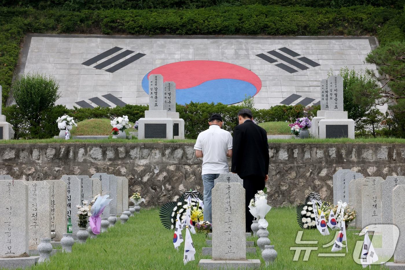 본문 이미지 - 현충일을 이틀 앞둔 4일 서울 동작구 국립서울현충원을 찾은 참배객들이 묘역에 참배하고 있다. 2026.6.4 ⓒ 뉴스1 이광호 기자