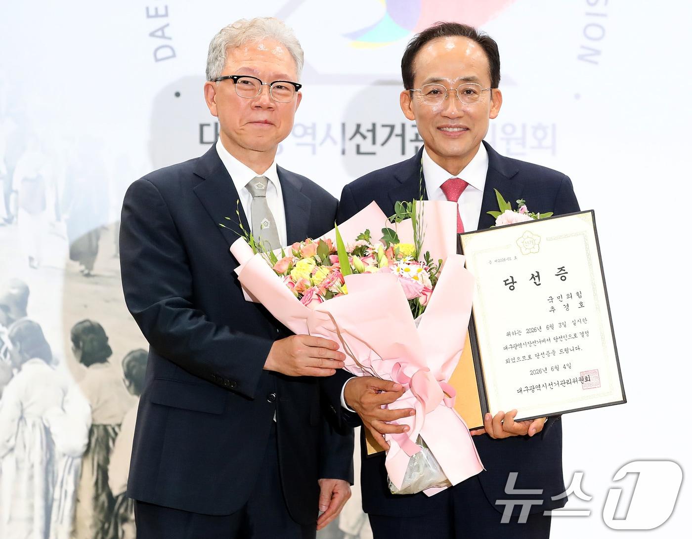 본문 이미지 - 추경호 국민의힘 대구시장 당선인(오른쪽)이 4일 오후 대구 서구 중리동 대구시선거관리위원회에서 열린 제9회 전국동시지방선거 당선증 교부식에 참석해 당선증을 받은 뒤 강동명 대구선관위원장과 기념 촬영을 하고 있다. 2026.6.4 ⓒ 뉴스1 공정식 기자