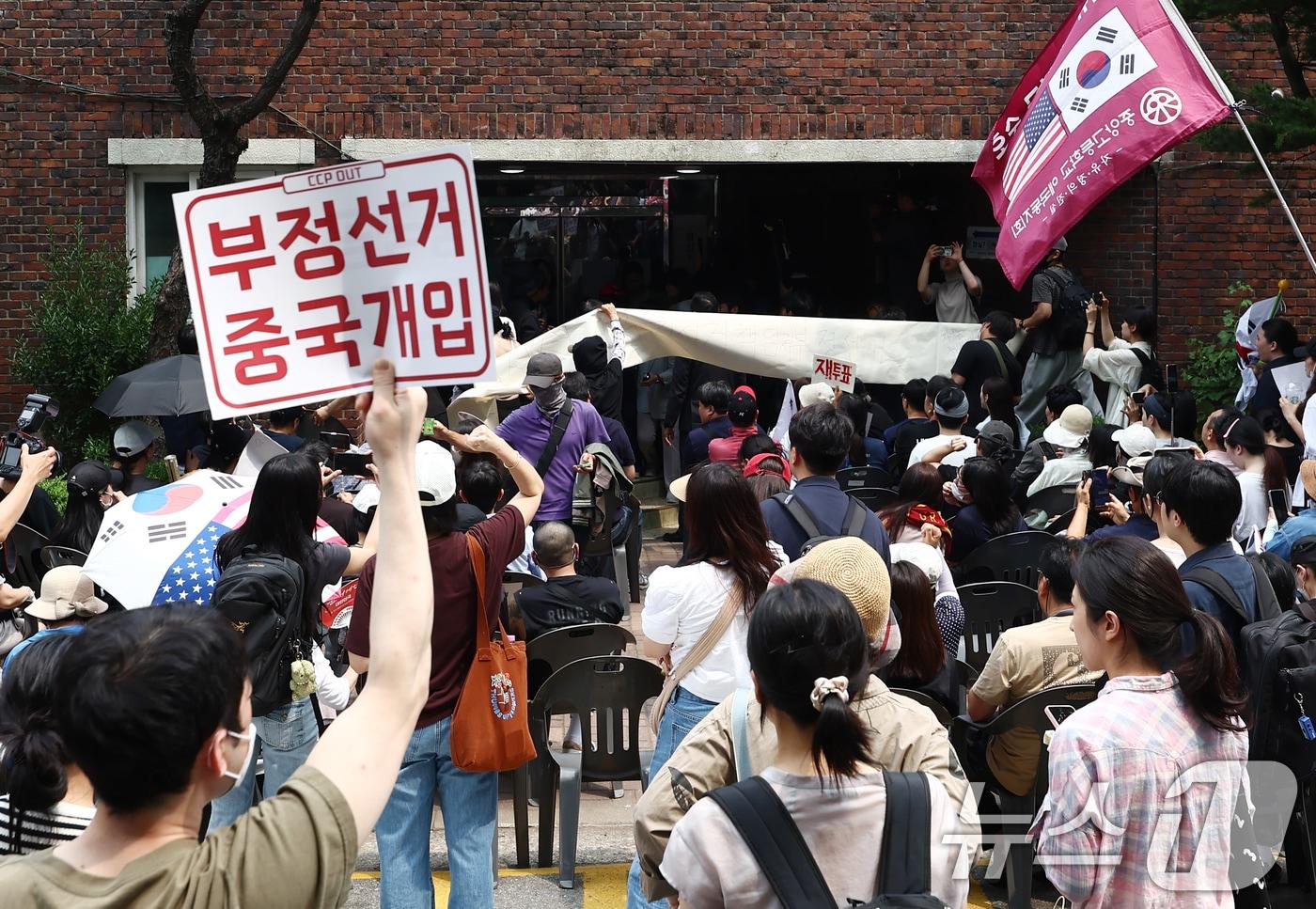 본문 이미지 - 4일 제9회 전국동시지방선거 및 국회의원 재·보궐선거 투표함 이송이 지연되고 있는 서울 송파구 잠실7동 제2투표소에서 시위대와 일부 주민들이 부정선거를 외치며 입구를 봉쇄하고 있다. 2026.6.4 ⓒ 뉴스1 김민지 기자