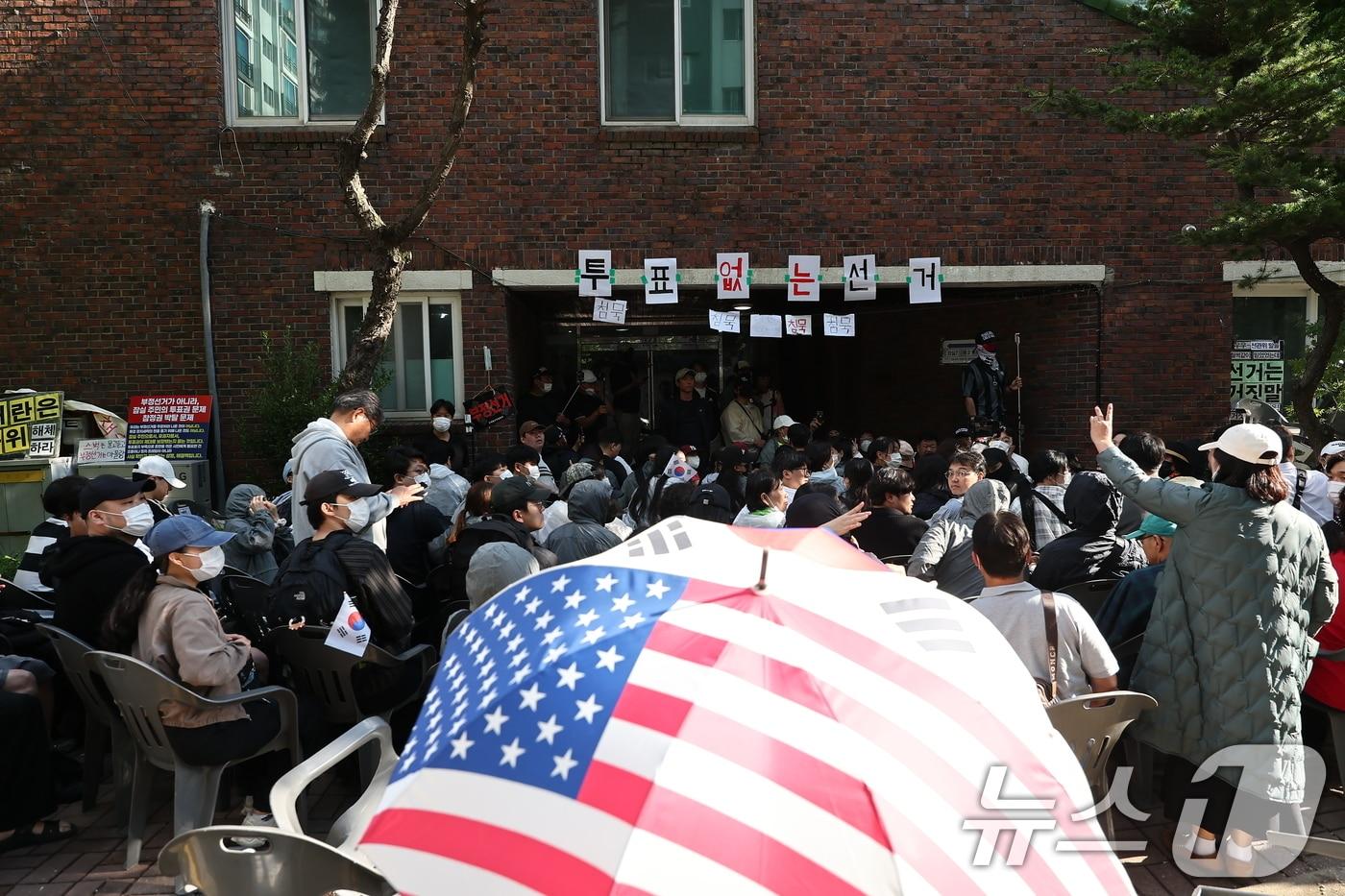 본문 이미지 - 5일 '투표용지 부족' 사태가 발생한 서울 송파구 잠실7동 제2투표소 앞에서 집회 참가자들이 투표함 반출을 막기 위해 경찰들과 대치하고 있다. 2026.6.5 ⓒ 뉴스1 김도우 기자