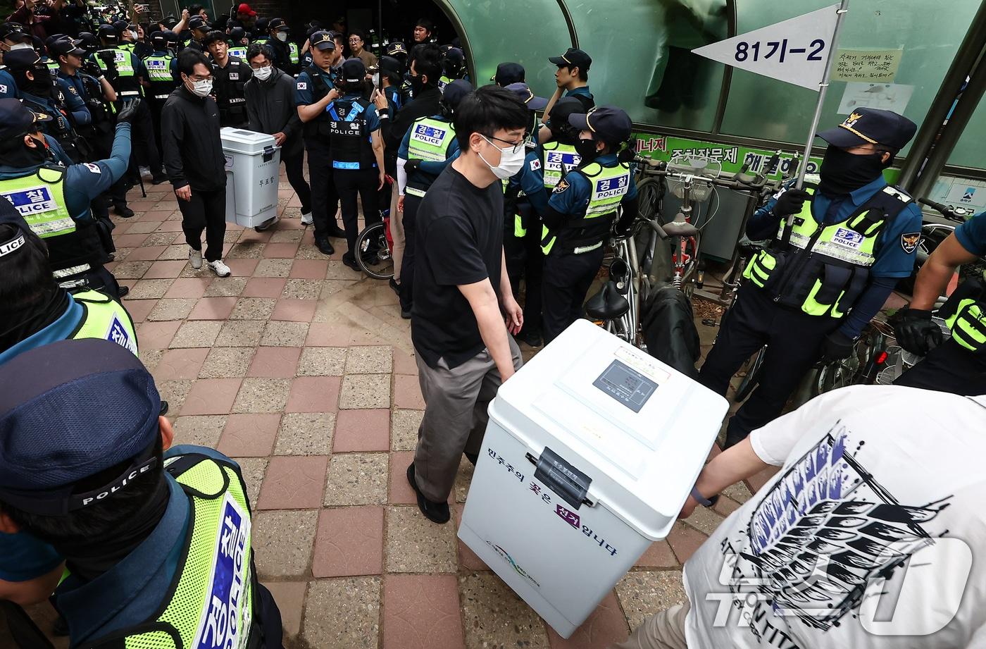 본문 이미지 - 5일 '투표용지 부족' 사태가 발생한 서울 송파구 잠실7동 제2투표소 앞에서 서울시선관위 관계자들이 투표함을 이송하고 있다. 2026.6.5 ⓒ 뉴스1 김도우 기자