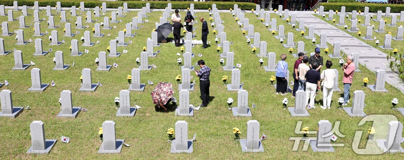 본문 이미지 - 현충일인 6일 전북 전주시 군경묘지를 찾은 추모객들이 참배를 하고 있다. 2026.6.6 ⓒ 뉴스1 유경석 기자