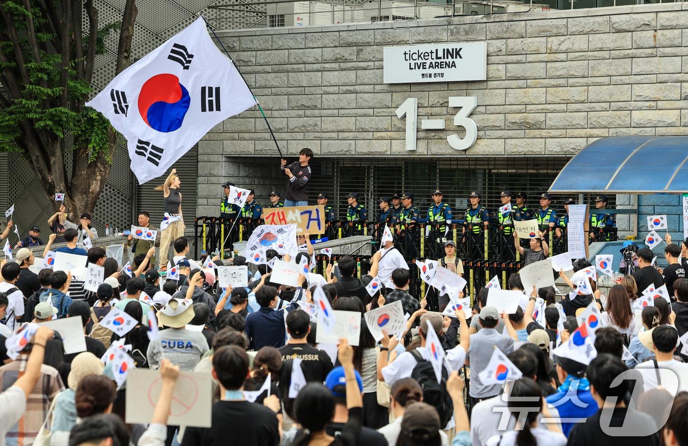 본문 이미지 - 제9회 전국동시지방선거 투표용지 부족 사태에 반발한 시민들이 7일 서울 송파구 올림픽공원 핸드볼경기장 개표소 앞에 모여 재선거를 요구하는 구호를 외치고 있다. 2026.6.7 ⓒ 뉴스1 이호윤 기자