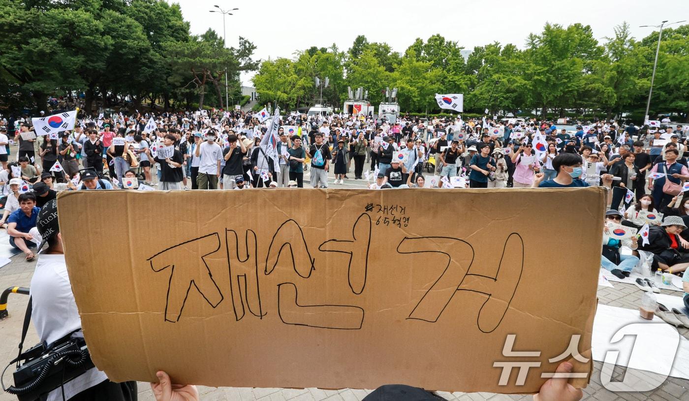 본문 이미지 - 제9회 전국동시지방선거 투표용지 부족 사태에 반발한 시민들이 7일 서울 송파구 올림픽공원 핸드볼경기장 개표소 앞에 모여 재선거를 요구하는 구호를 외치고 있다. 2026.6.7 ⓒ 뉴스1 이호윤 기자