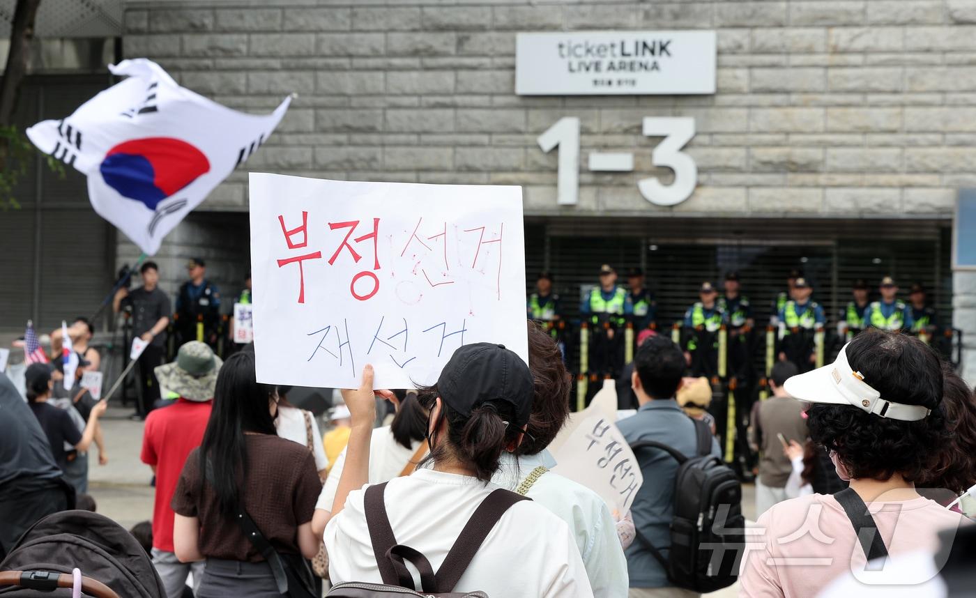 본문 이미지 - 제9회 전국동시지방선거 투표용지 부족 사태를 규탄하며 재선거를 요구하는 집회가 계속되고 있는 8일 서울 송파구 올림픽공원 핸드볼경기장 개표소 앞에 모여 재선거를 요구하는 구호를 외치고 있다. 2026.6.8 ⓒ 뉴스1 김진환 기자